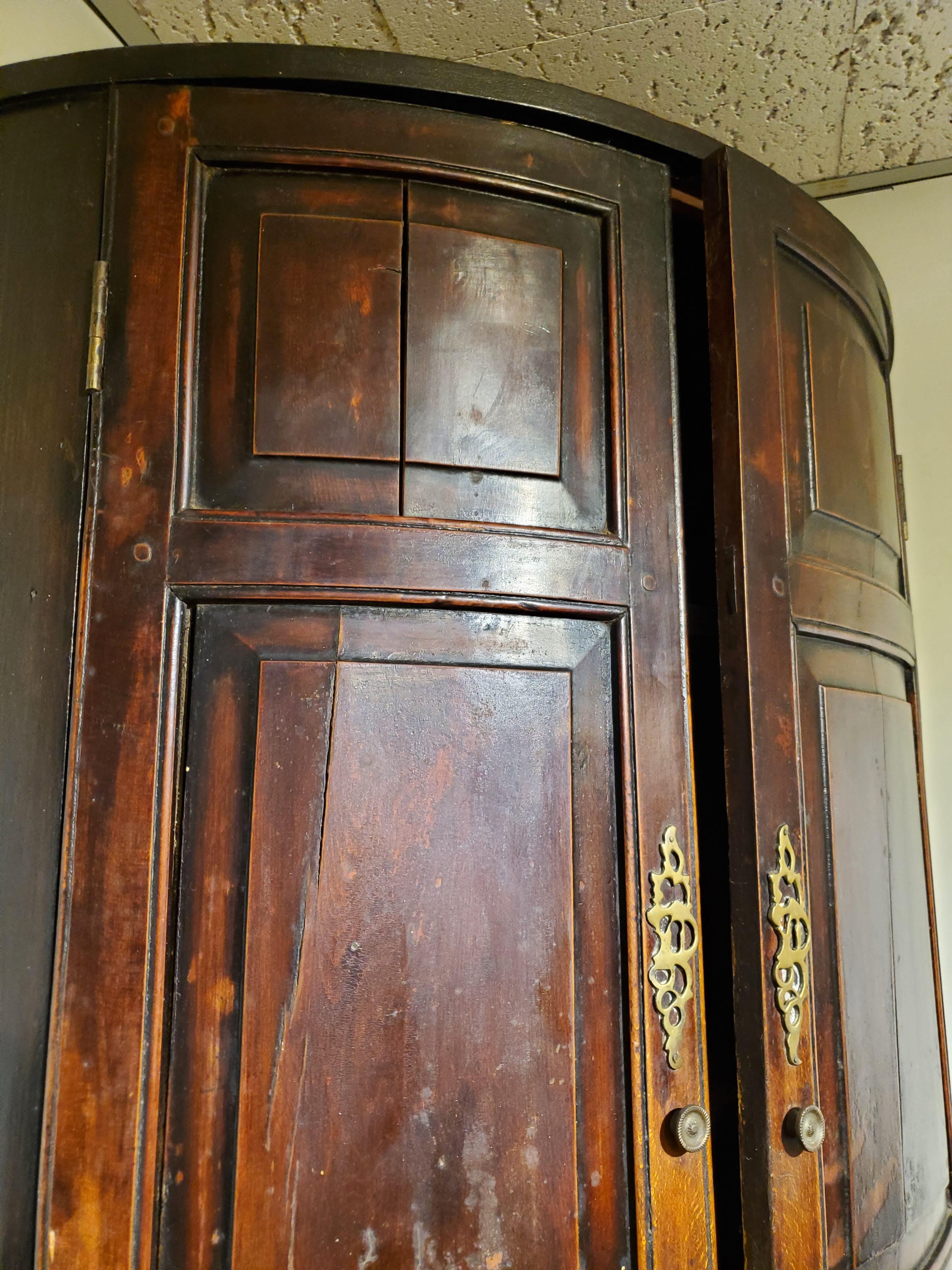 18th century George III English bow front corner cupboard. Made of deeply patinated beech wood with a lustrous color. Elegant proportions retaining the original brass hardware with interior decorative shaped shelves. 
England, circa