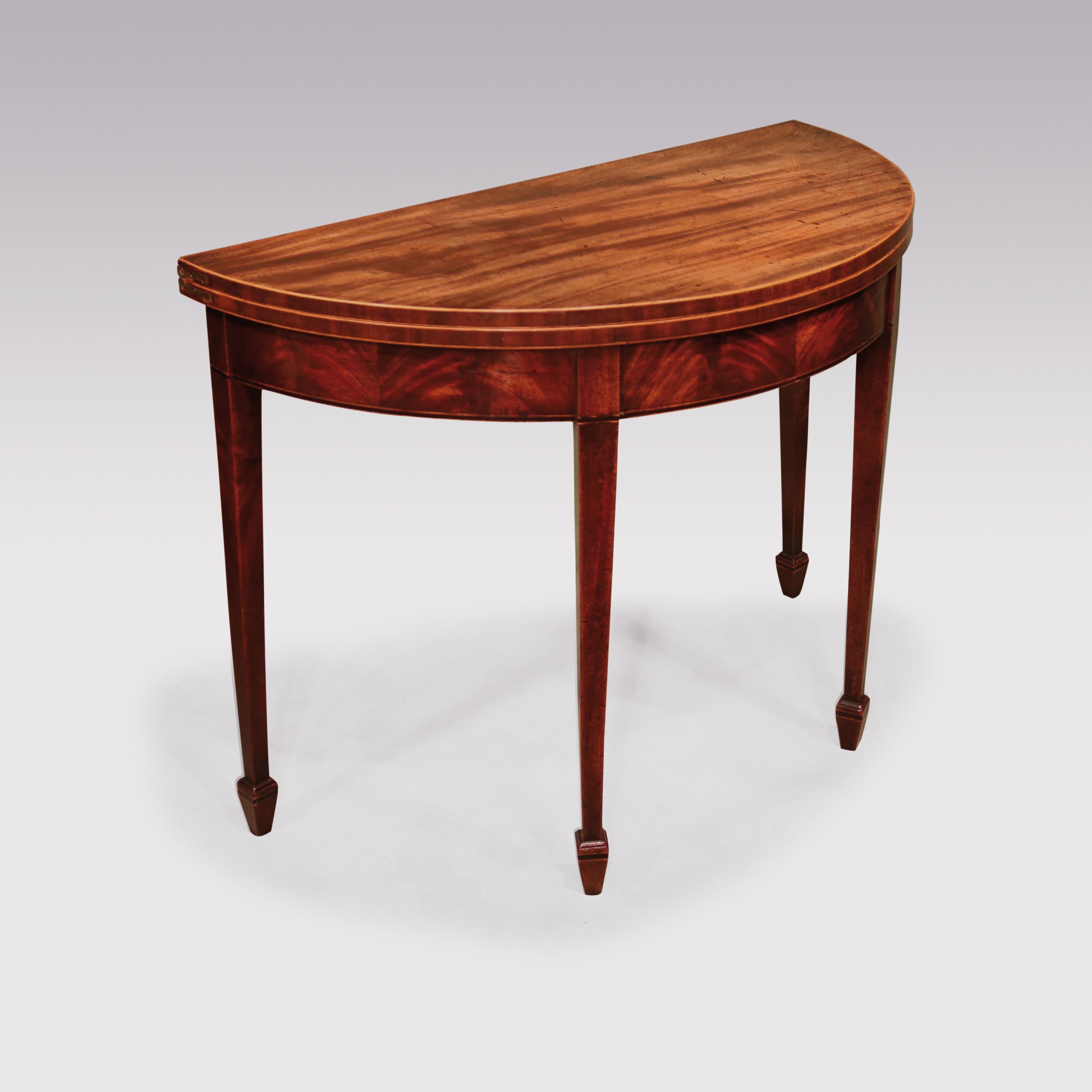 A late 18th century well figured mahogany half round card table with boxwood edging to top, enclosing green baize playing surface, supported on square tapering legs ending on boxwood and ebony strung spade toes.

  