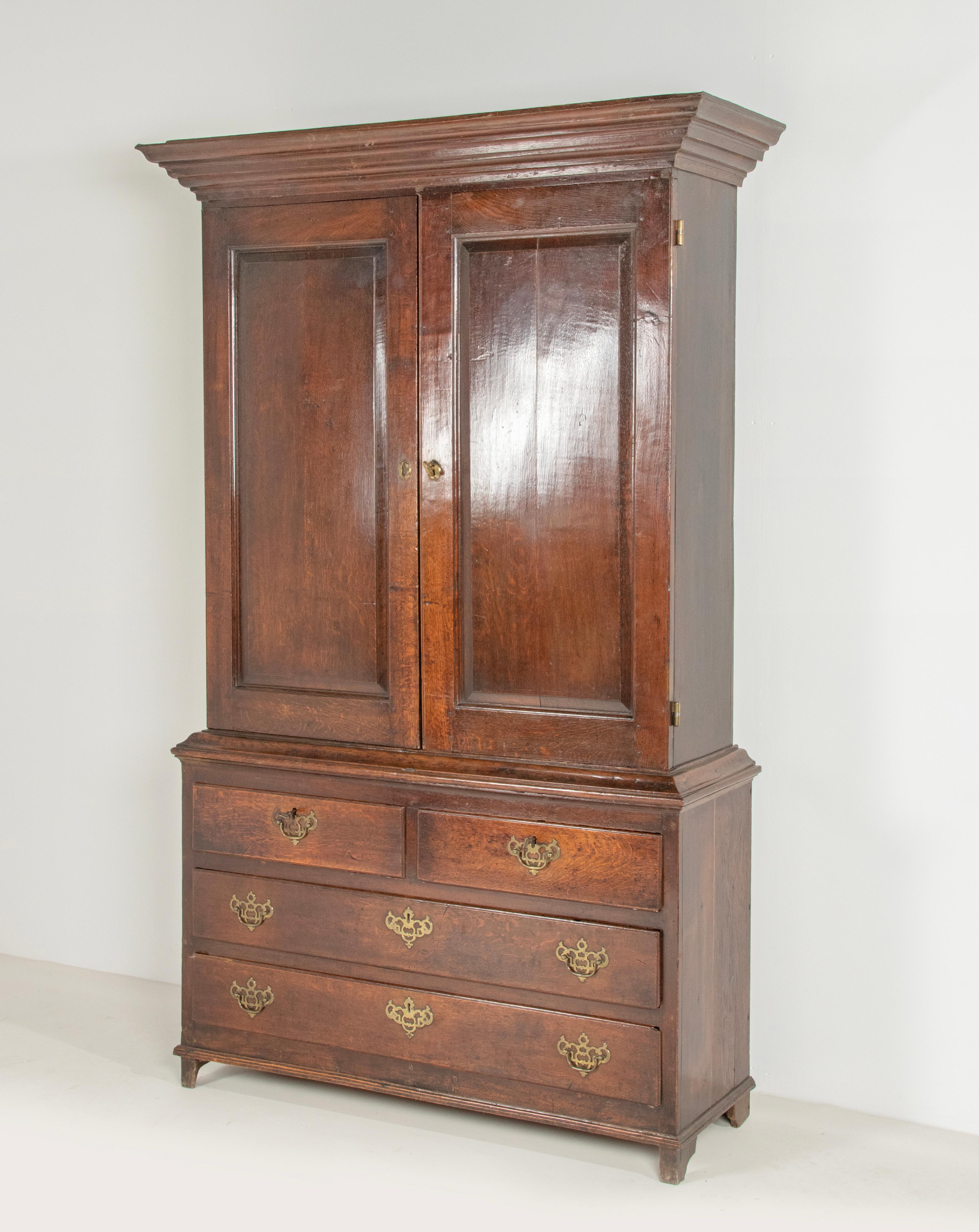 Late 18th century oak cupboard, The top part has two doors with fielded panels. The lower part has four drawers with brass handles. The cabinet has a beautiful old and shiny patina with a beautiful warm red color. The interior of the cabinet