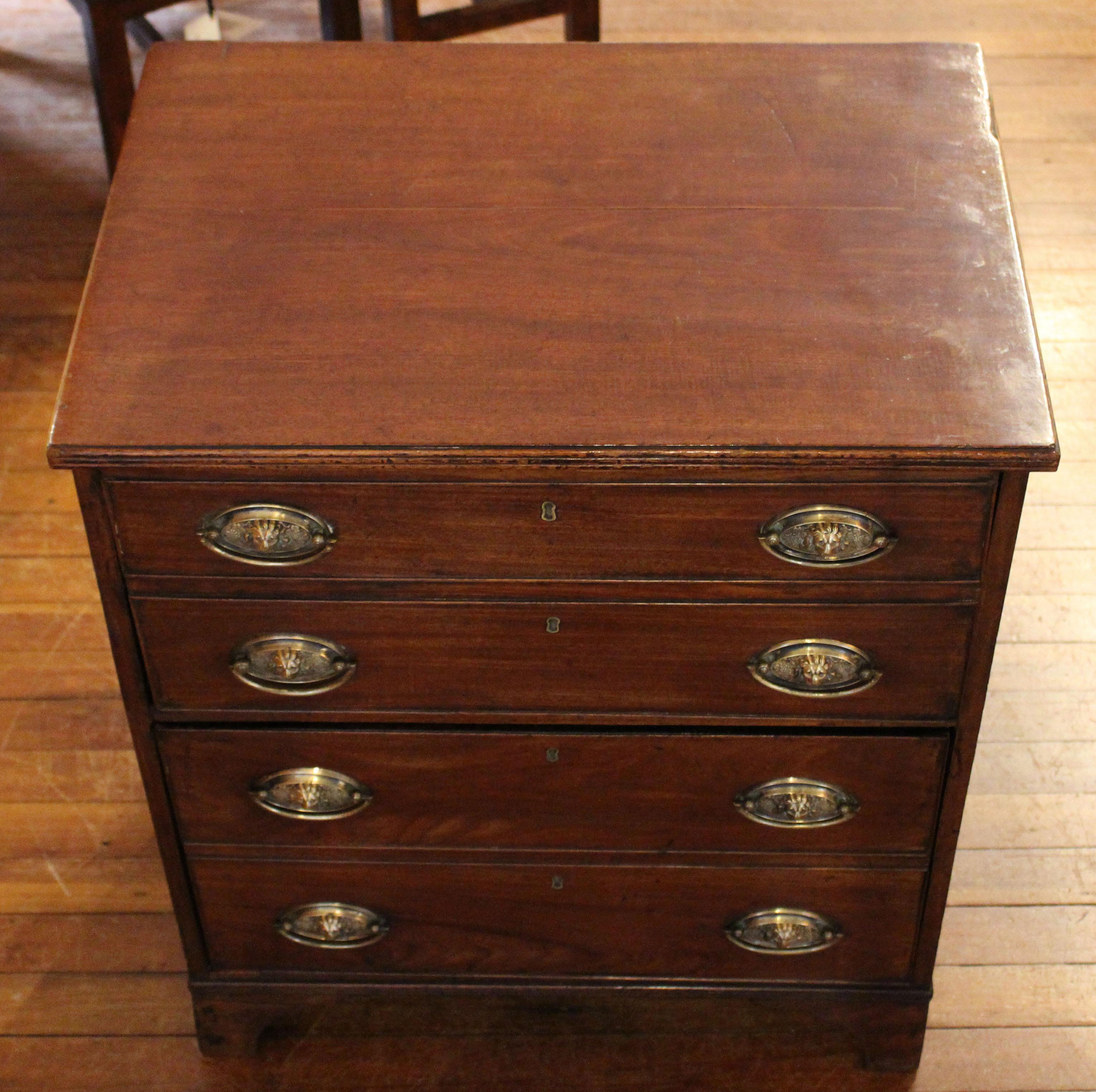 Late 18th century Georgian small chest of drawers raised on shaped bracket feet. Reeded top and base moldings. English. Lion mask oval brass pulls. Converted from a lift top commode to two deep drawers each with two faux drawer fronts. Measures: 25