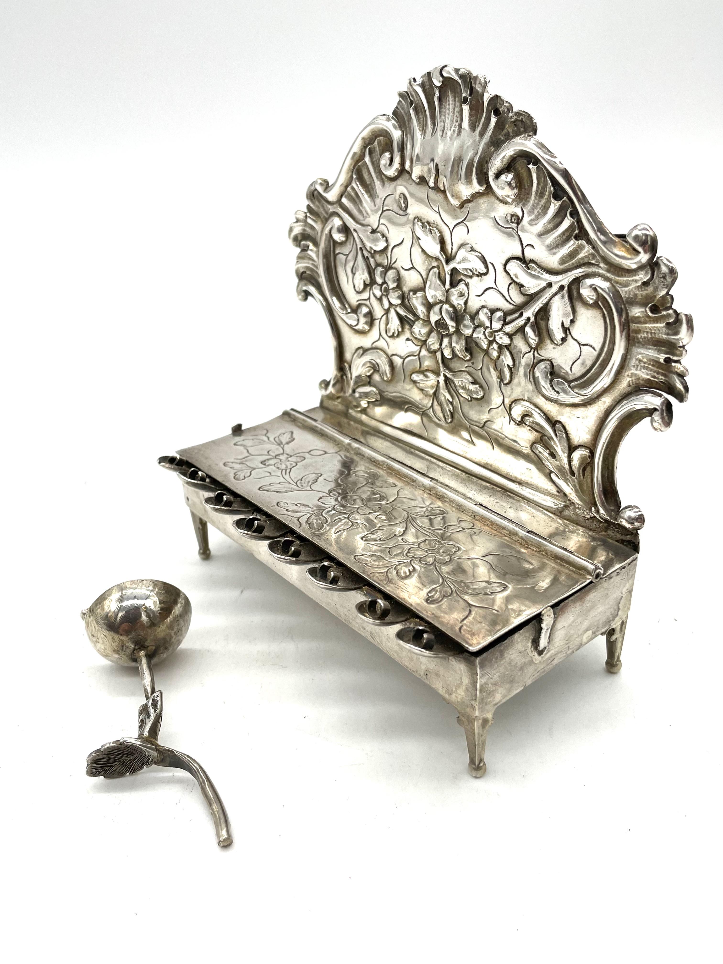 A late 18th century German silver Hanukkah lamp. This magnificent Hanukkah lamp has a shaped rococo cartouche backplate, chased with a swag of flowers and arched edges. The rectangle box containing the eight candle holders stands on four bracket
