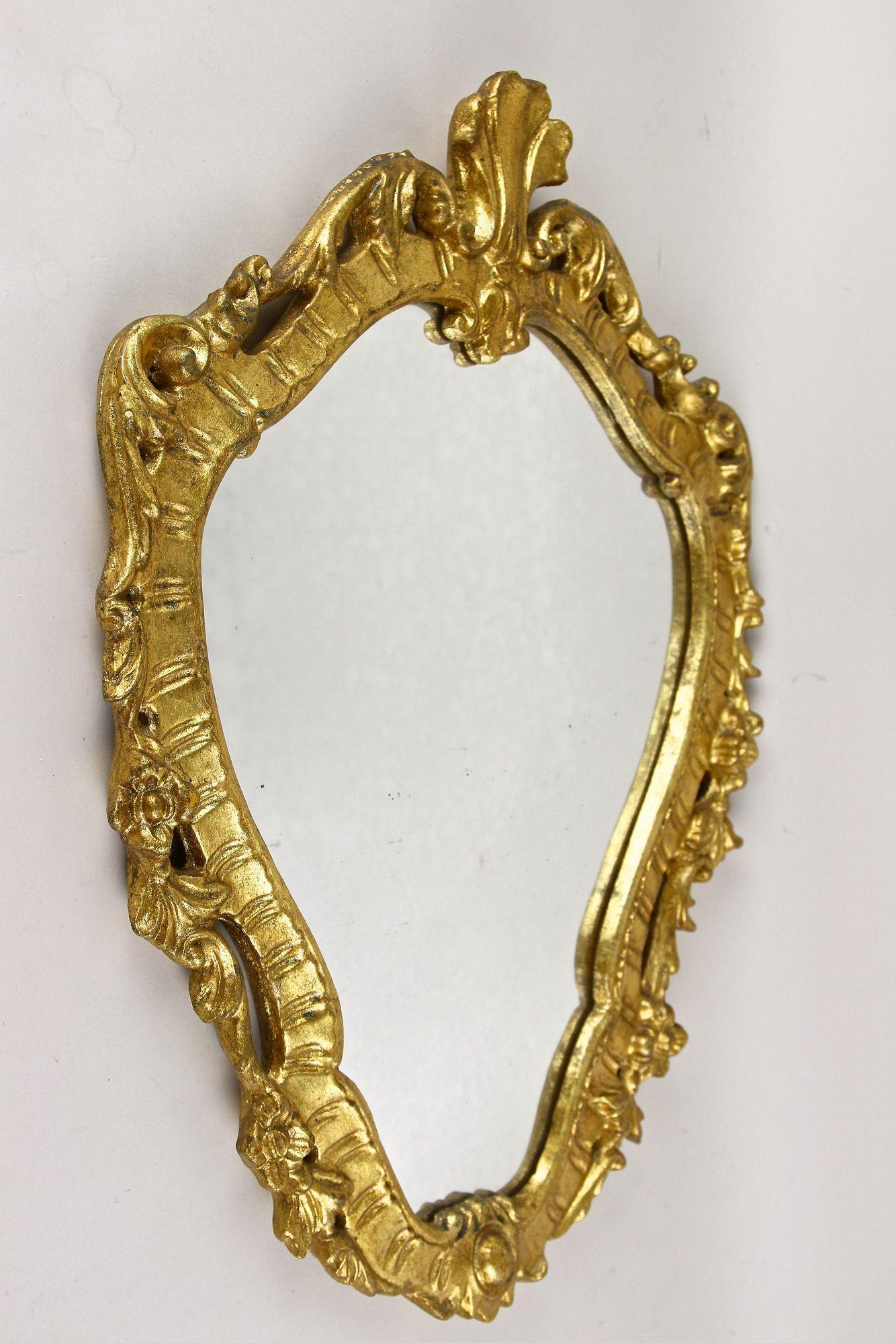 Elegante espejo de pared dorado del siglo XVIII, de finales del periodo barroco, hacia 1790 en Italia. El marco, artísticamente tallado a mano y parcialmente abierto, muestra una preciosa superficie chapada en pan de oro y está adornado con motivos