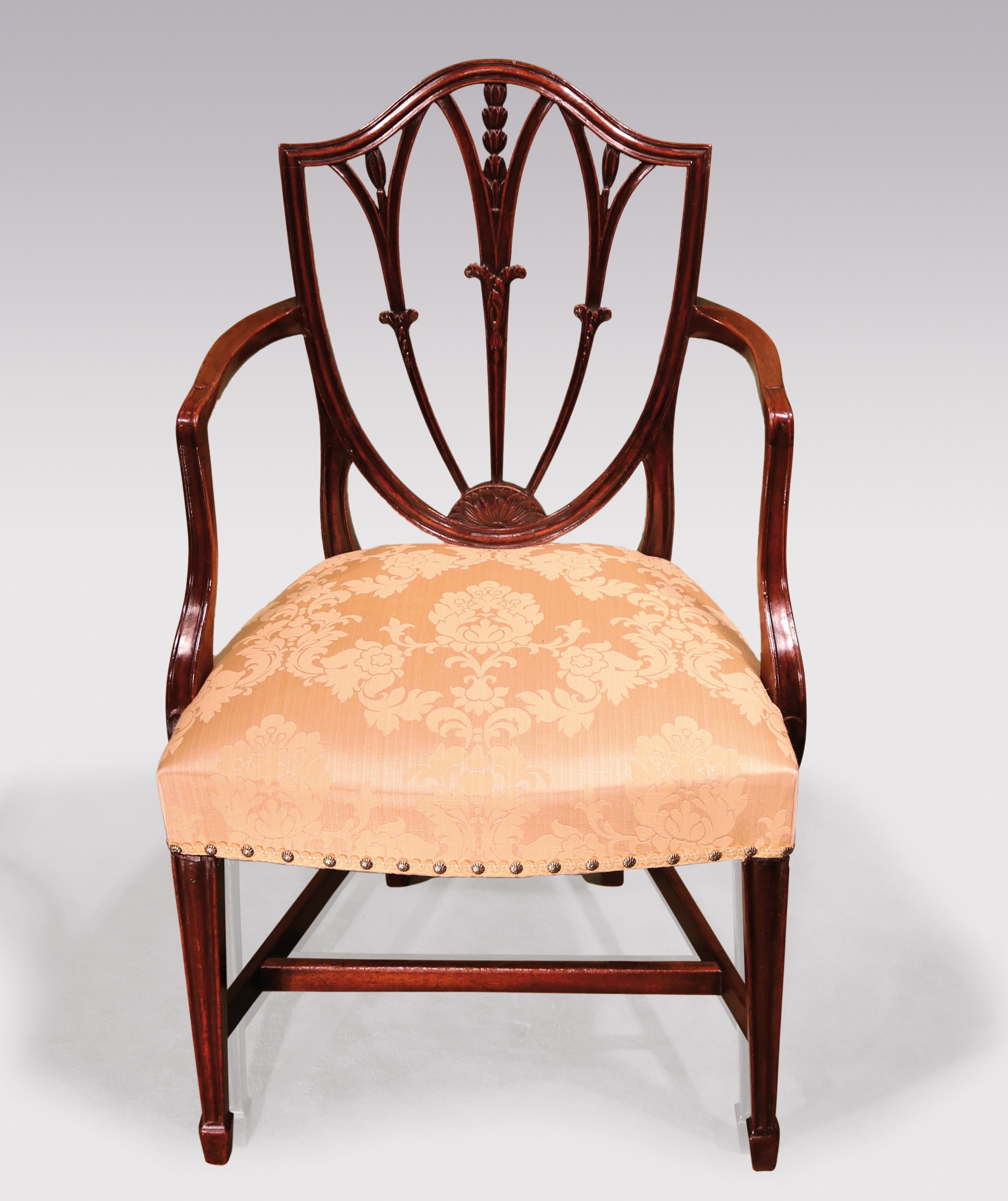 A late 18th century Hepplewhite period mahogany armchair having moulded shield shaped back enclosing triple splats carved with leaves and husks radiating from sunburst panel. The chair having moulded set-back arms, supported on moulded square
