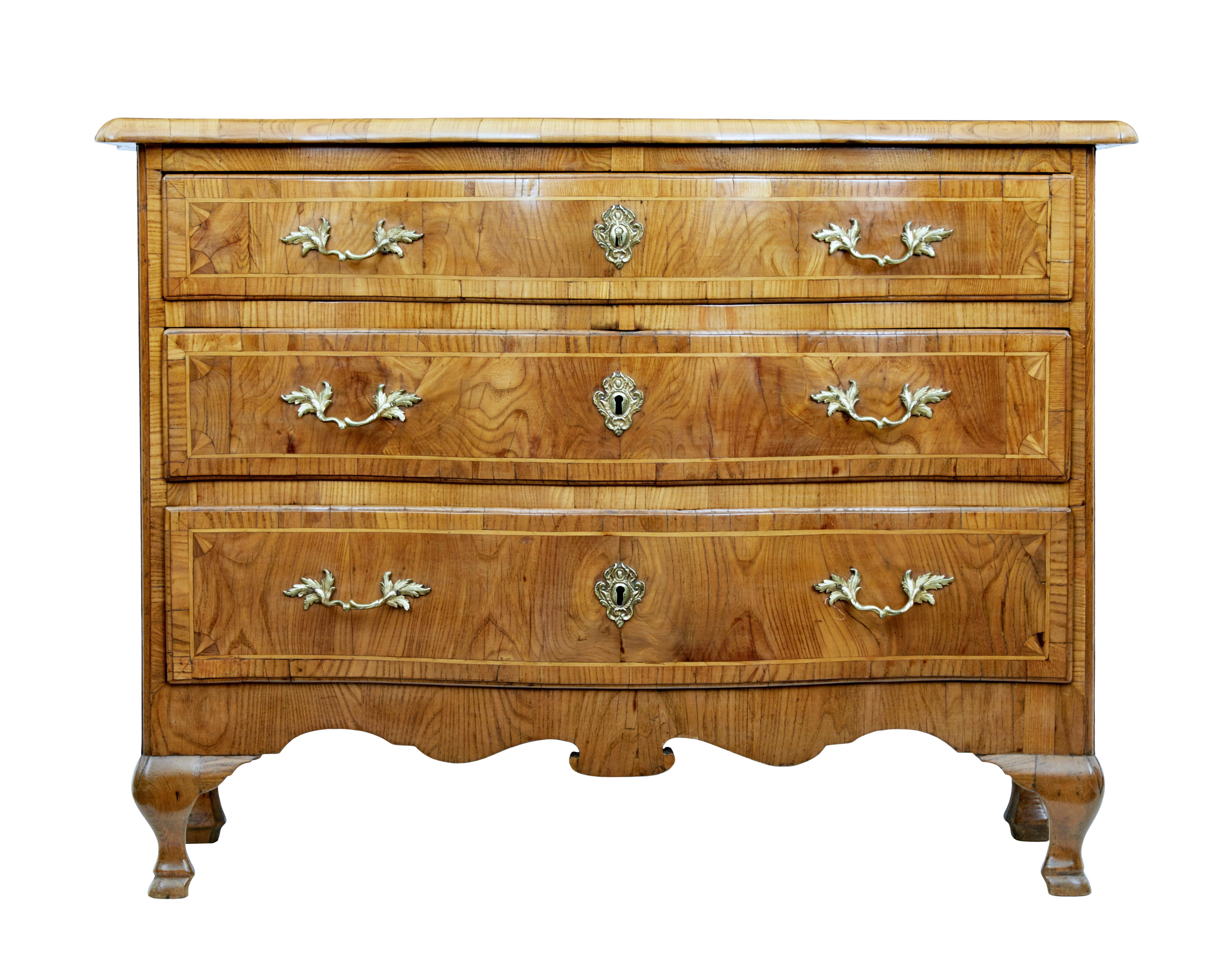 Glorious Rococo period elm commode circa 1780.

Bowfront shaped 3-drawer chest. Shaped over-sailing top which has been crossbanded and strung, complete with a double diamond pattern.

3 graduating drawers in burr elm with ornate handles and