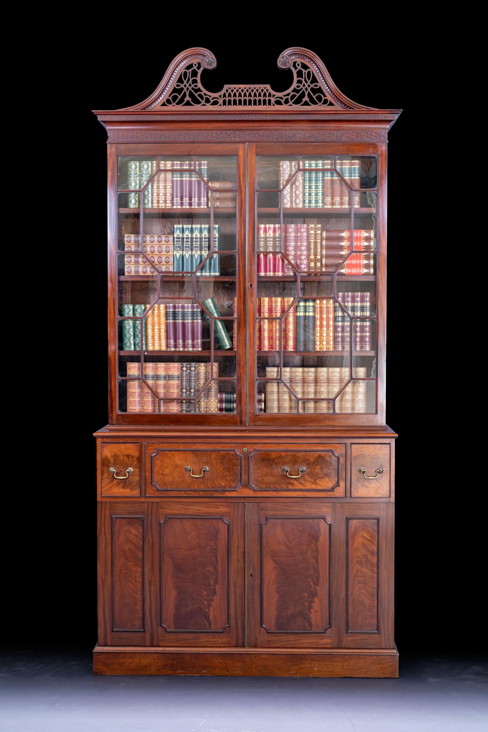 A superb Irish Georgian secretaire bookcase, the pierced swan necked cornice above a pair of astragal glazed doors containing adjustable shelves with fitted secretaire drawer flanked by two short drawers and cupboards on platform support.

Circa