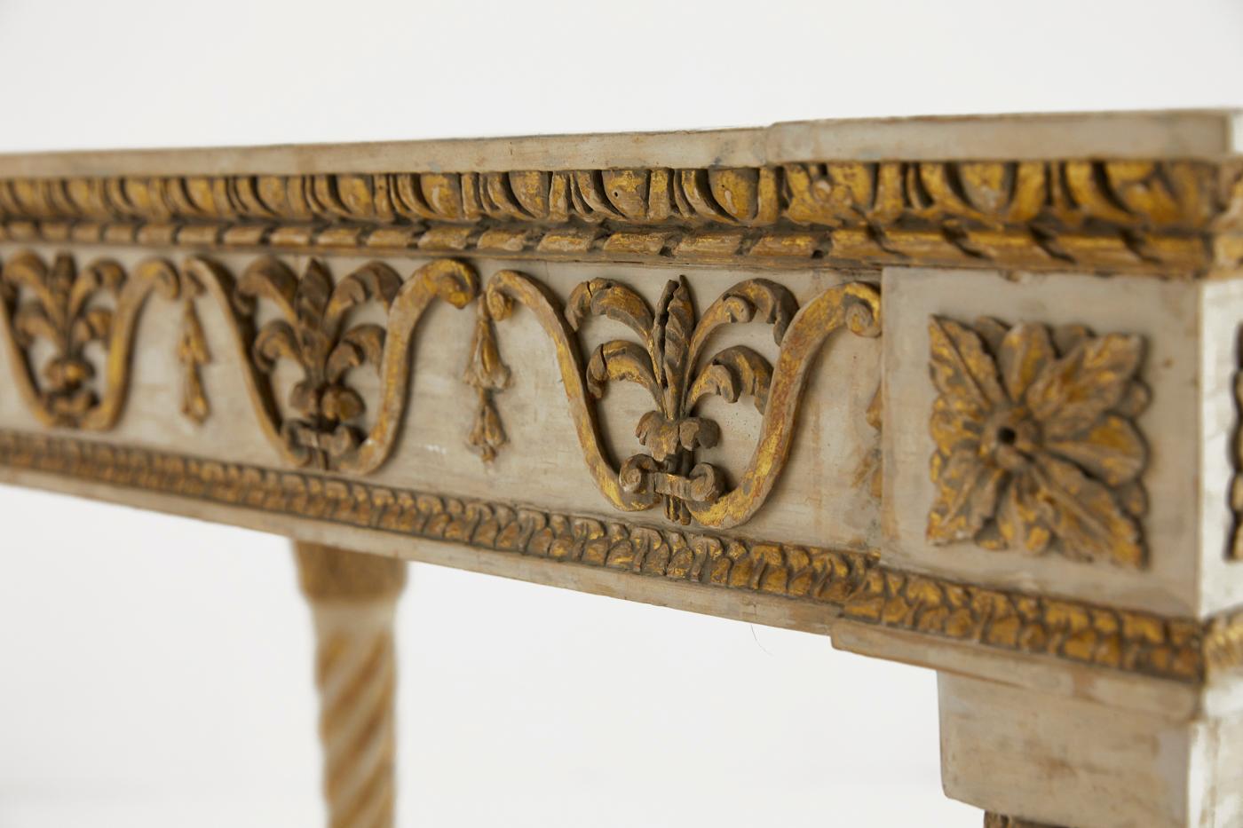 A late 18th-early 19th century Italian carved giltwood and off white painted console table with simulated marble top.