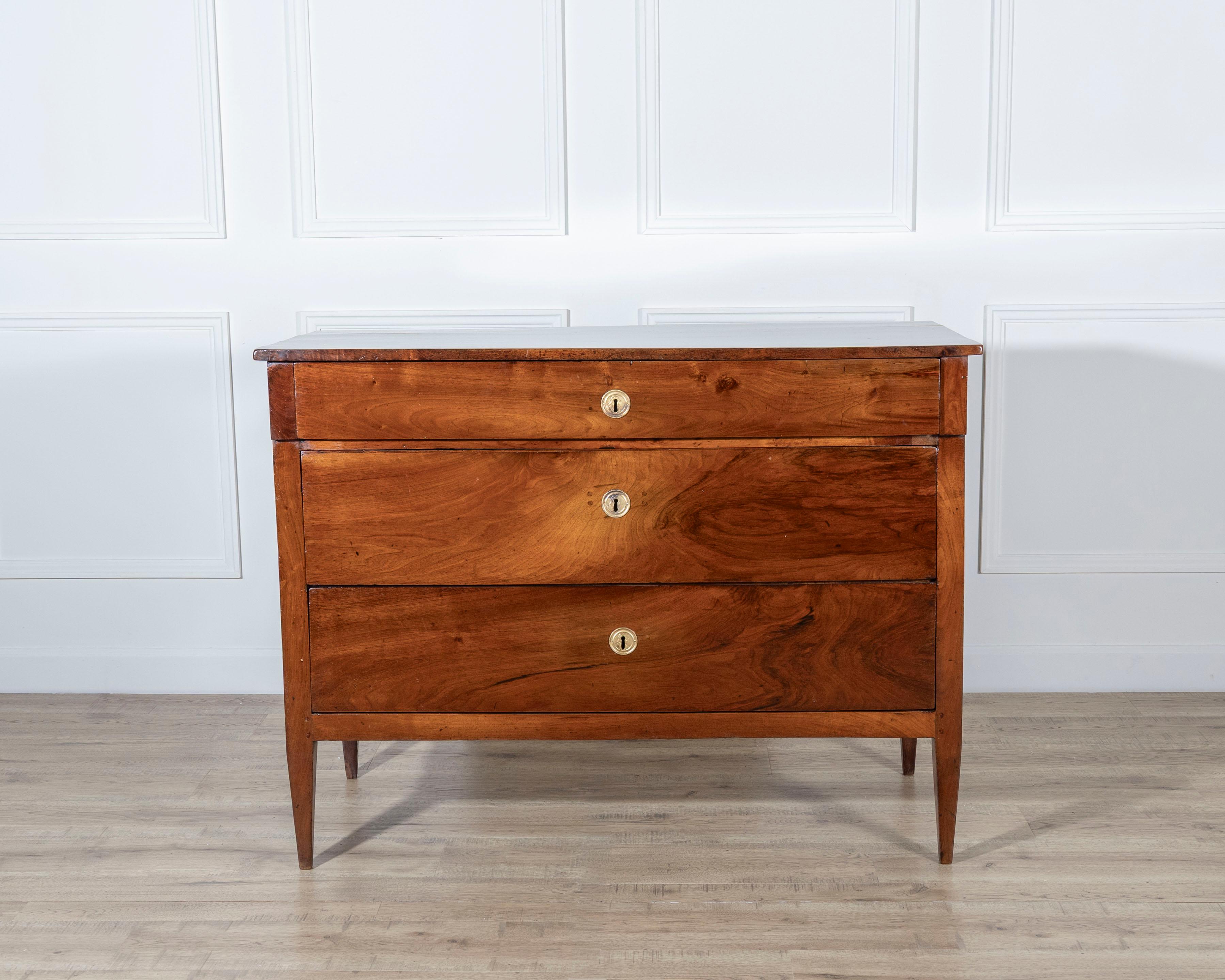 An elegant Italian Directoire chest of drawers from the late 18th century, originating from the Emilia Romagna region and crafted entirely in solid walnut. This refined piece reflects the transitional aesthetic between Neoclassicism and Empire,