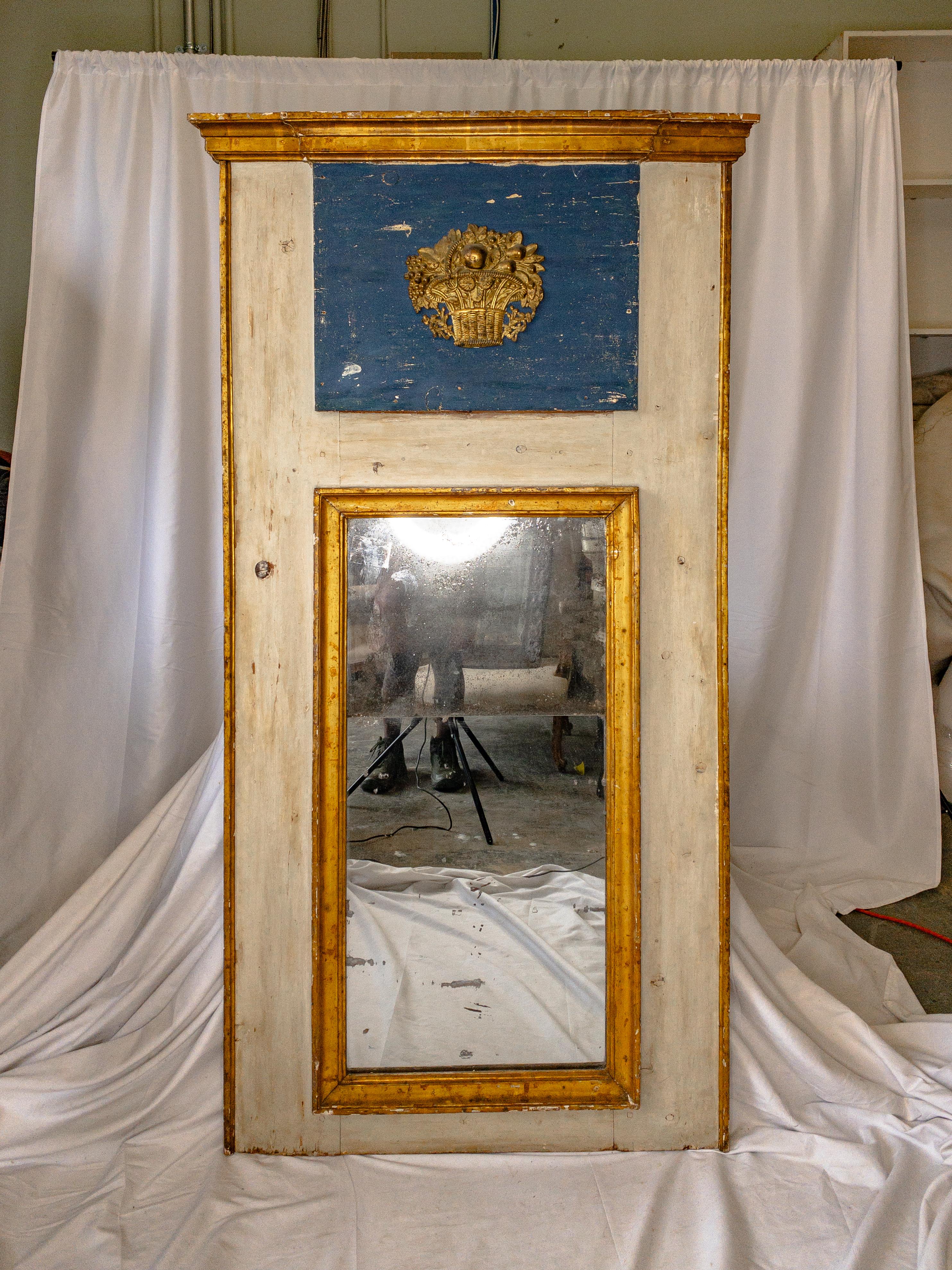 This late 18th-century Italian trumeau mirror is a stunning exemplar of neoclassical elegance. Its elongated form, painted in a serene antique white hue, exudes a sense of grace and refinement. The focal point of the mirror, positioned at the top