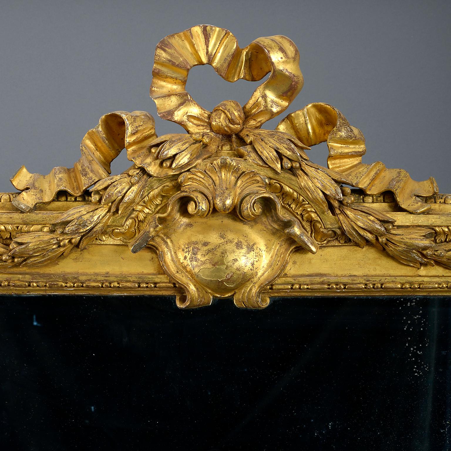 Großer Spiegelrahmen aus vergoldetem Holz aus dem späten 18. Jahrhundert, geschnitzt im Stil des frühen Louis XVI, mit einem Band, dessen Wappen von einer Kartusche zentriert wird, und einer Schürze, die mit einem Rosen- und Lilienzweig beschnitzt