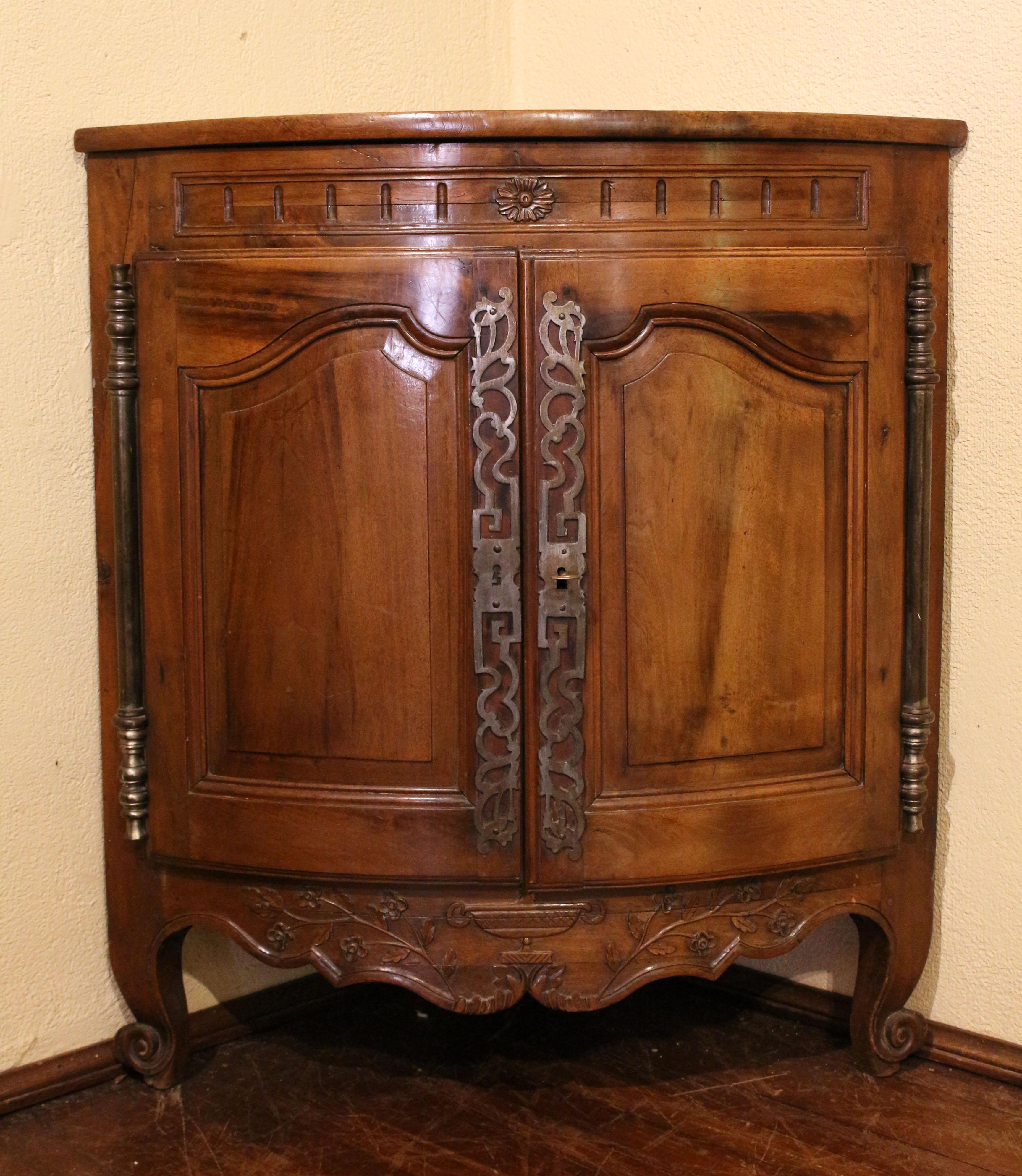 Late 18th century Louis XVI period encoigneur (corner cabinet), French. Walnut. Bowfront form. Extensive steel hardware. Bold escargot carved whorl feet. Shaped, molded doors, surmounted by a colonette frieze with central rosette over Grecian urn &