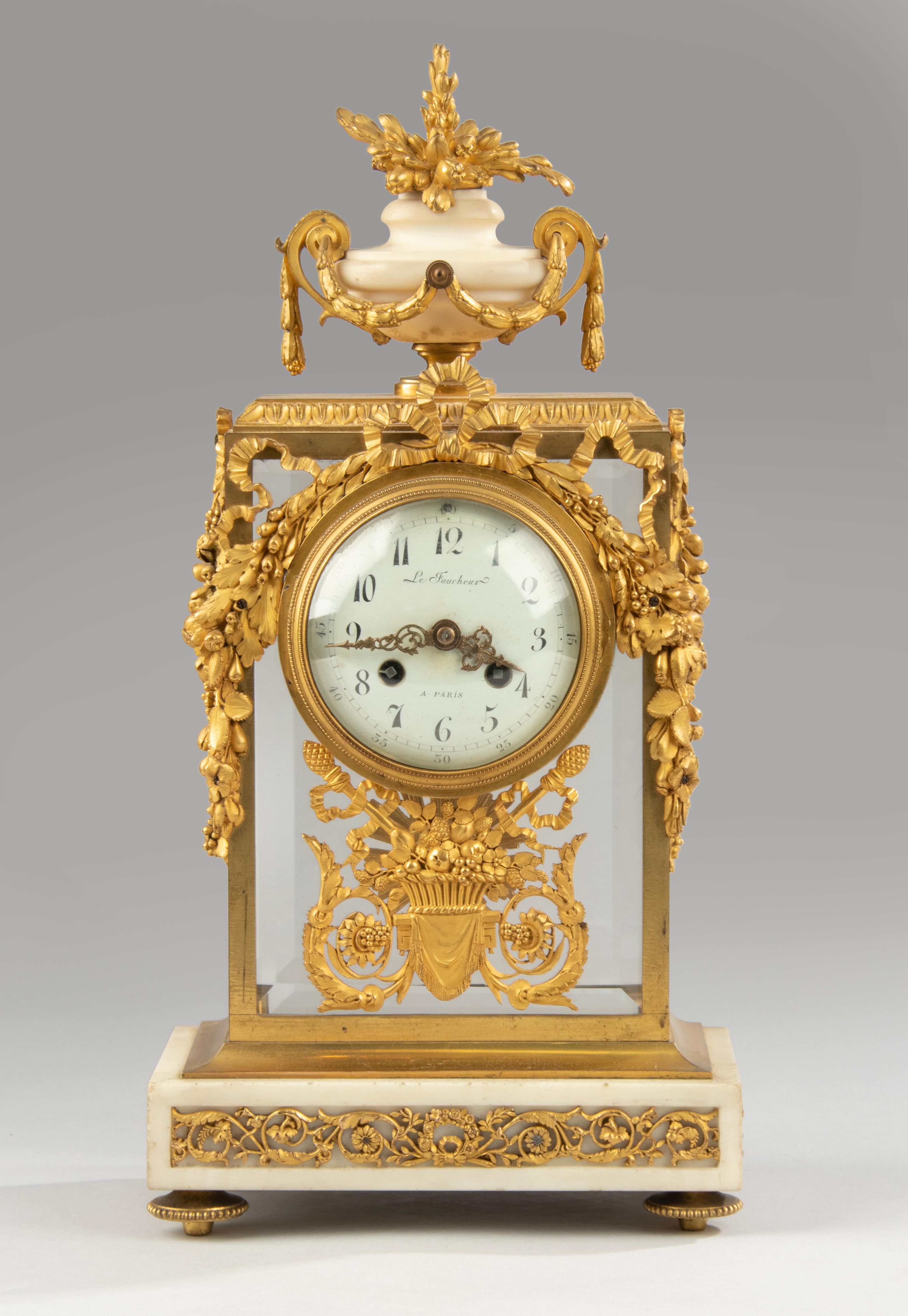 A finely bronze fire-gilded ormolu mantel clock set with matching candelabras. Rich ornate with typical Louis XVI mounts, floral garlands, scrolls, ribbons and bow. The case is made of gilt brass with beveled glass all around, on white marble base.