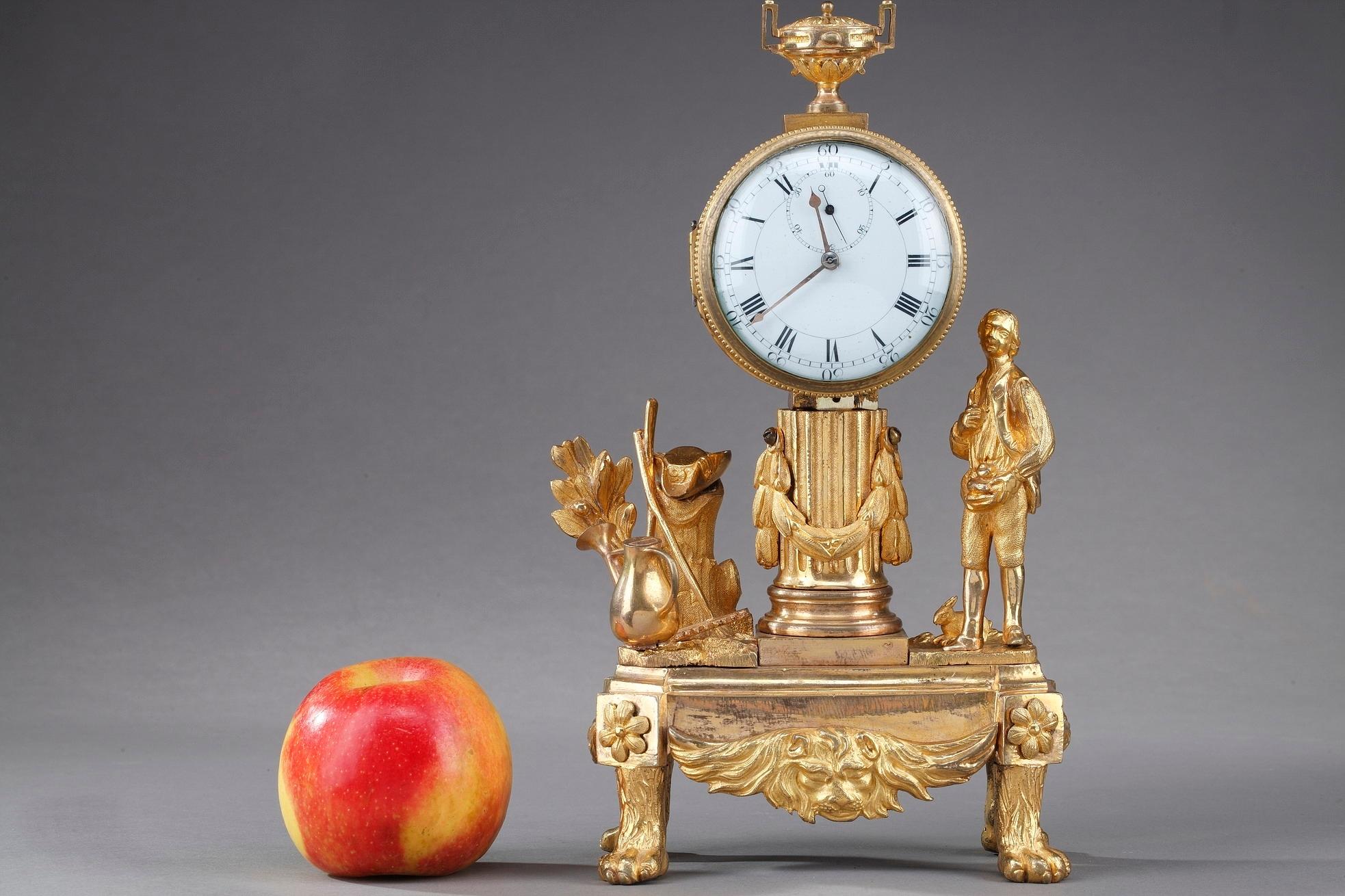 Small mantle clock crafted of gilt bronze, or ormolu, featuring an allegory of the gardener. He is surrounded by a rabbit and some gardening tools: a watering can, a shovel and a rake. The pastoral subject illustrates the taste of Jean-Jacques