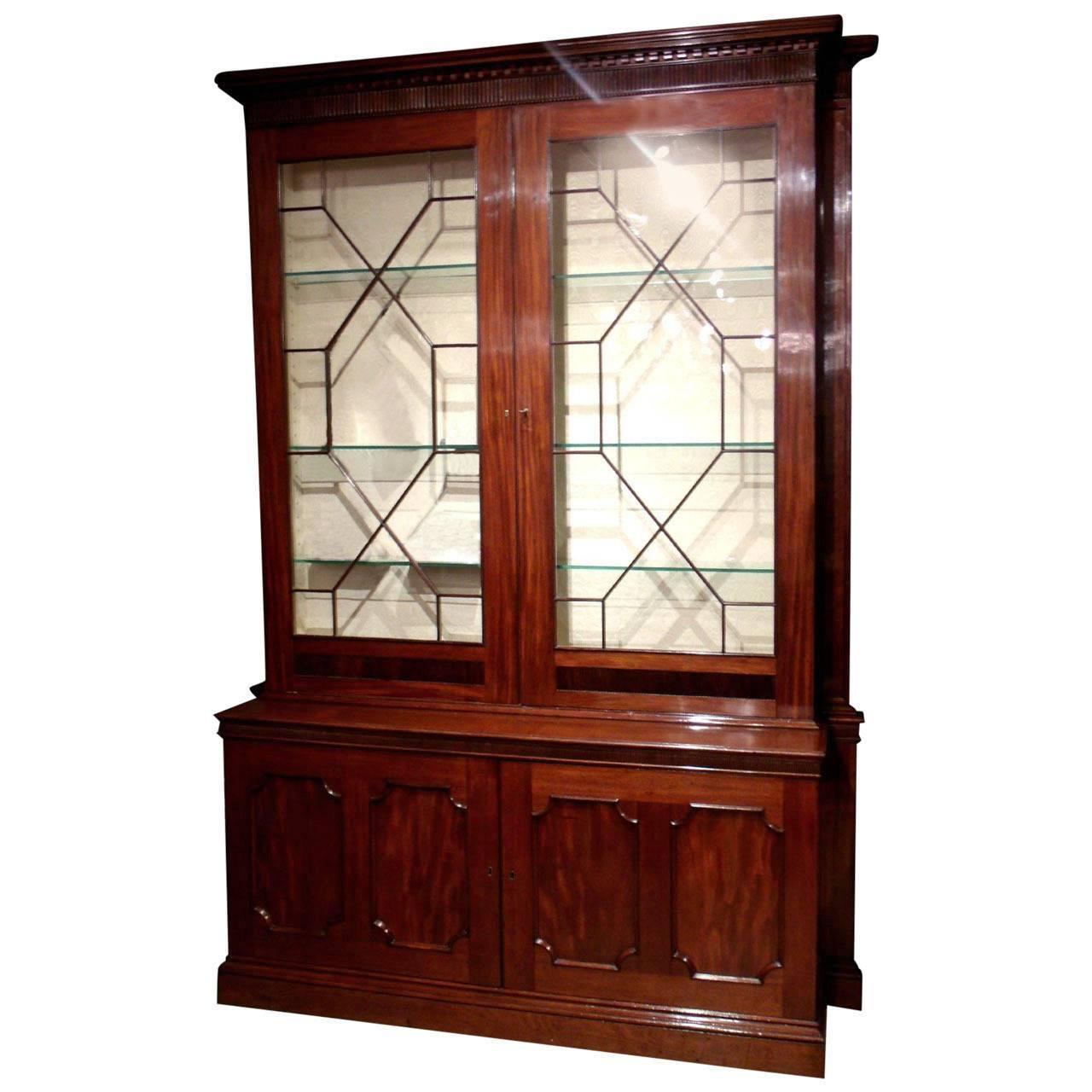 This superb quality and imposing mahogany bookcase with dentil cornice detailing has providence from Cound Hall in Shropshire. The top half of the bookcase is lined in a cream moiré silk with Astragal glazing on the doors and the bottom half