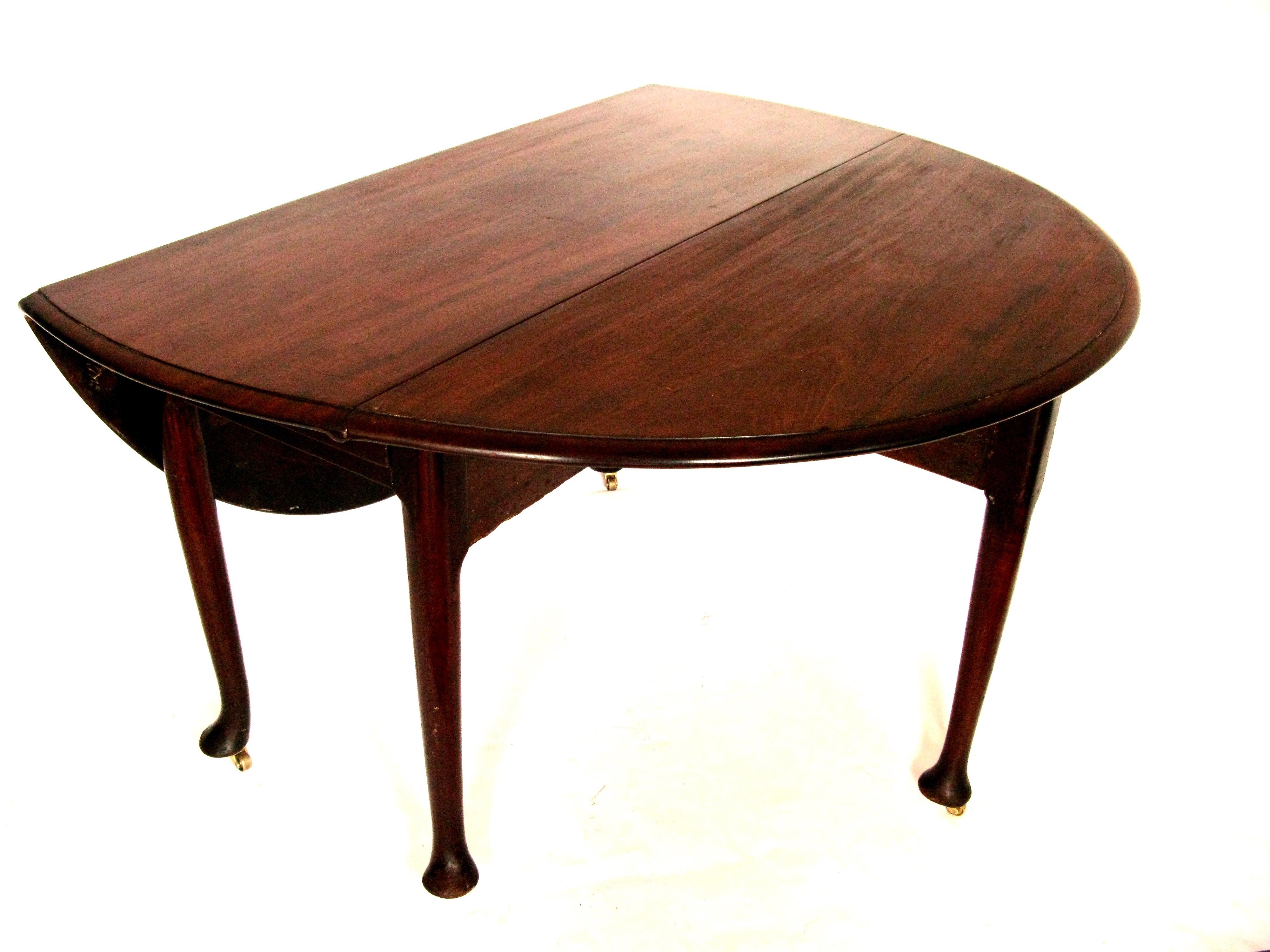 George III mahogany drop-leaf dining table, circa 1760. With solid mahogany top and leaves with curved edges, standing on 4 legs which finish on a simple pad foot with castors to ease to use the table. One pair of legs swing out on wooden hinges to