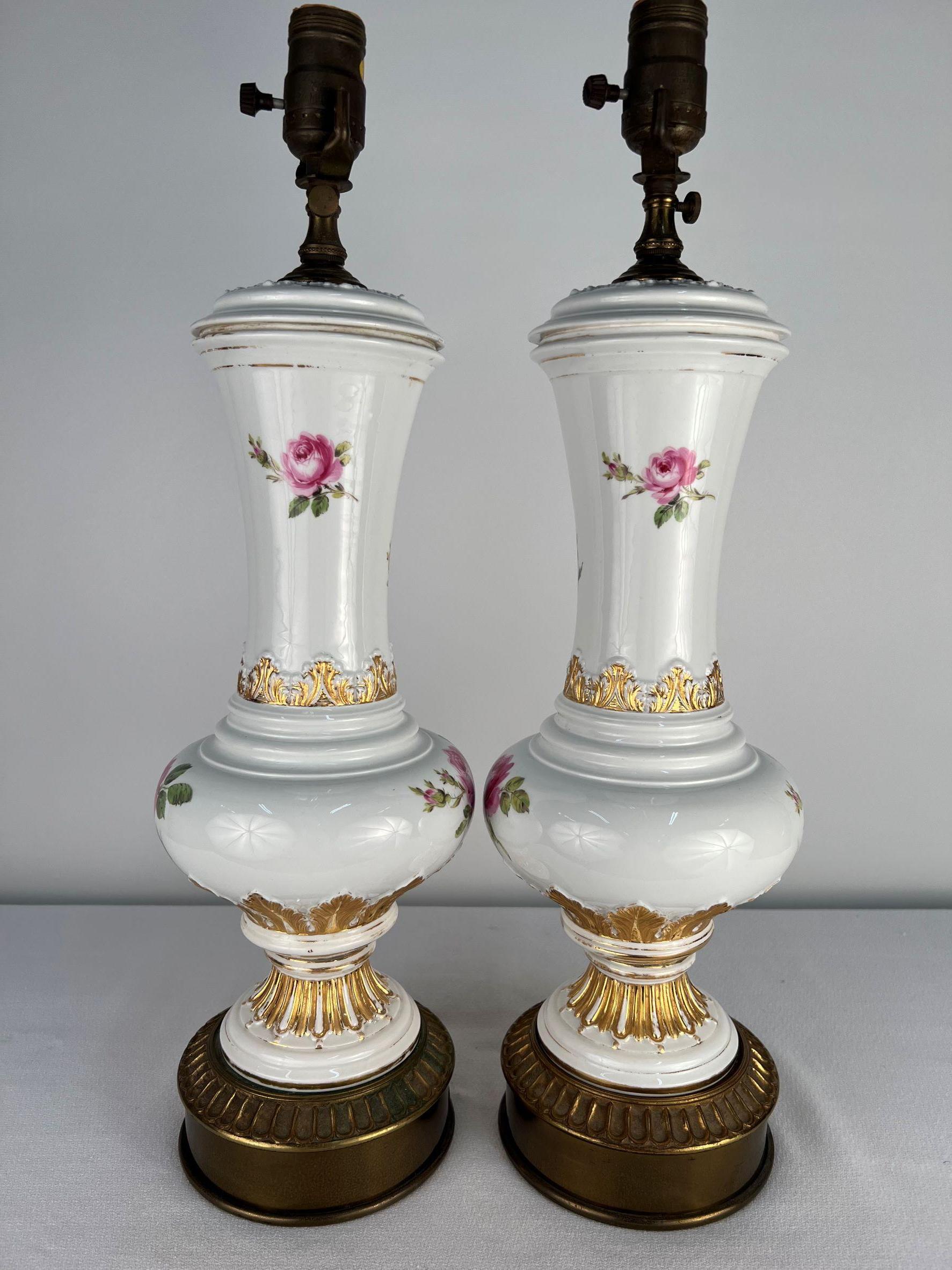 A charming pair of Meissen vases turned into table lamps featuring hand painted red roses, leaves and gilt acanthus details from the estate of Doris Day. One can imagine that Ms. Day and her decorator shopped and chose this particular pair of