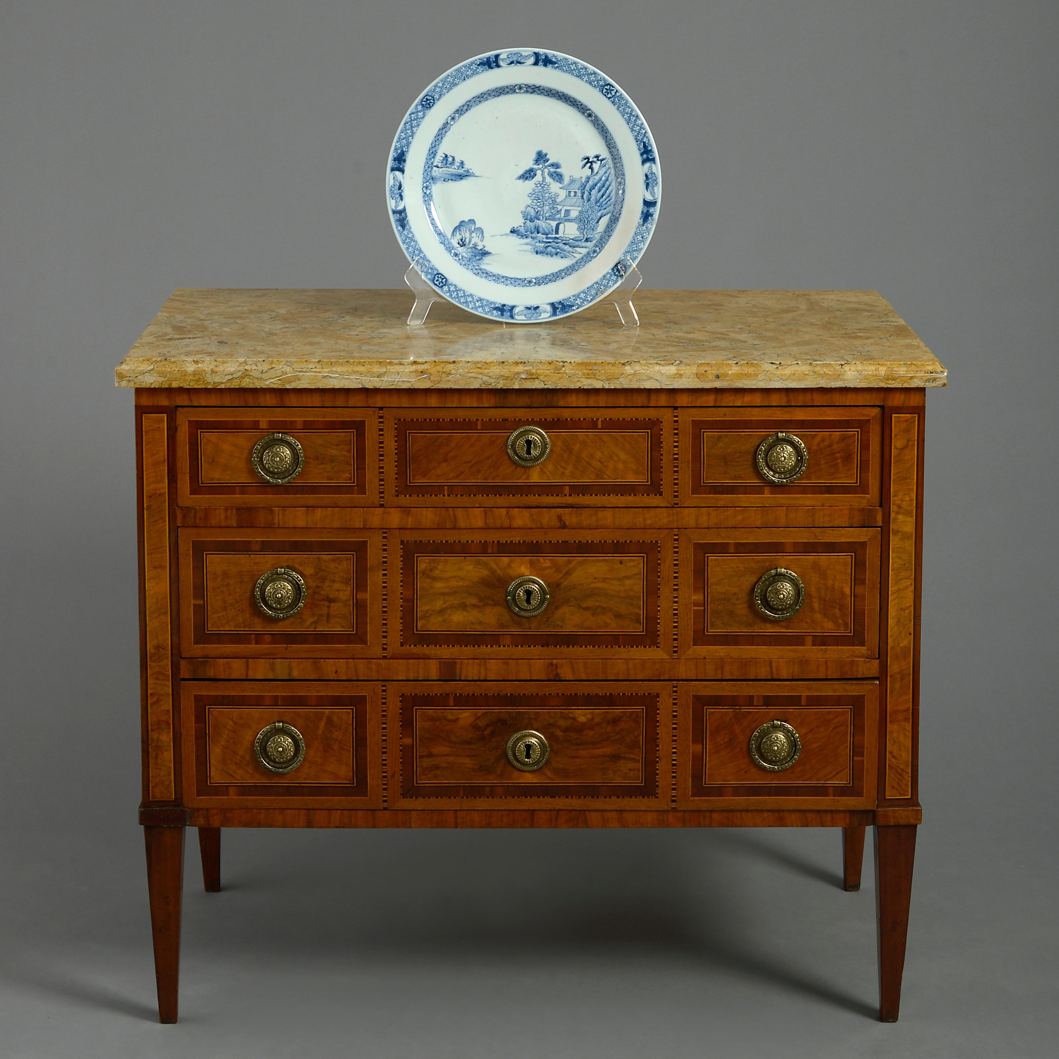 A fine late 19th century commode in the neoclassical taste, the figured marble top above three drawers with medallion brass handles and lock escutcheons, the front and sides all veneered in walnut, tulipwood and boxwood paneling and raised on square