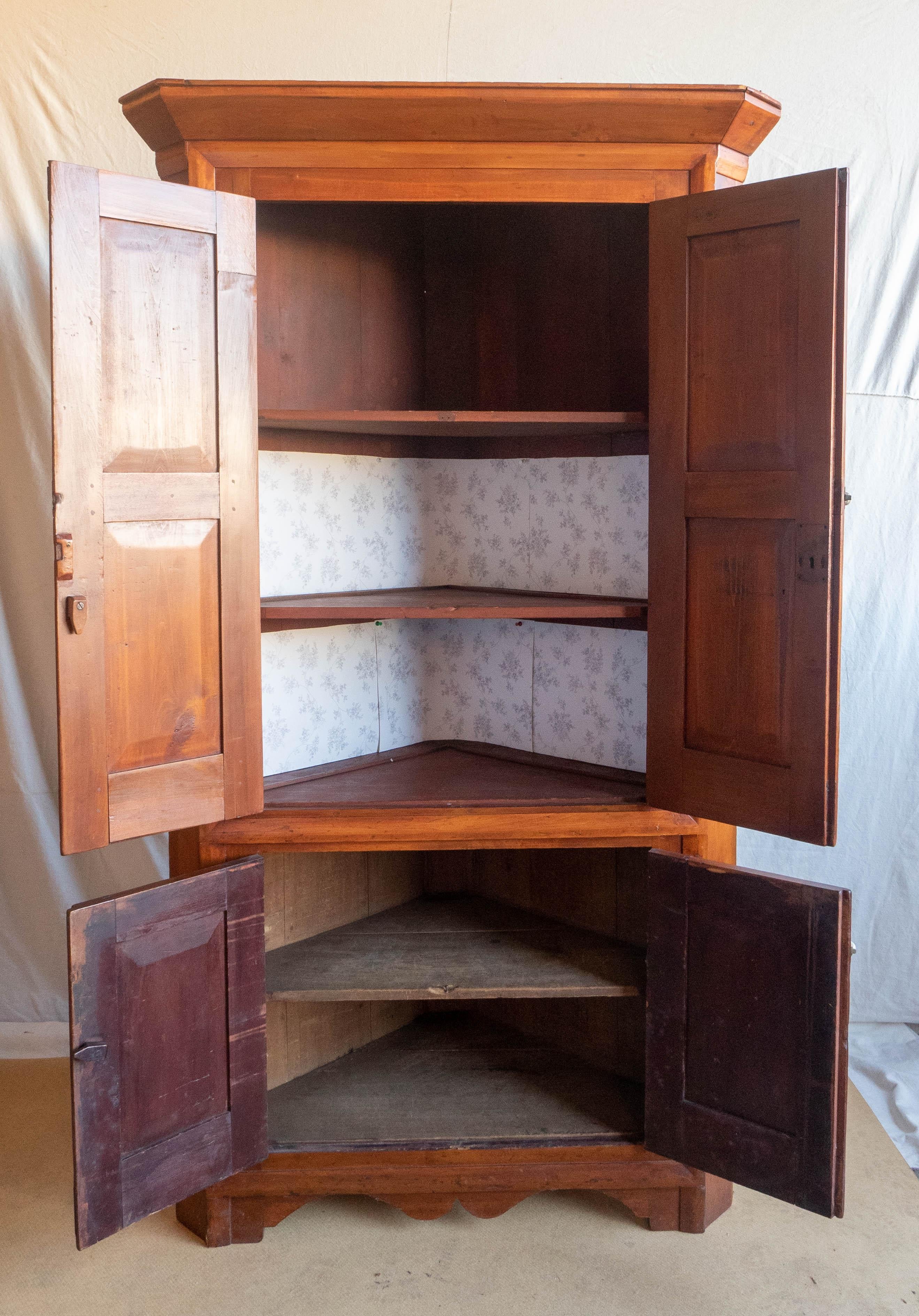Late 18th century New England cherry corner cupboard, circa 1790, a well proportioned one-piece cabinet having a strong crown molding above two pair of blind doors, flanked by canted sides, over a fluted apron, raised on bracket feet; the interior