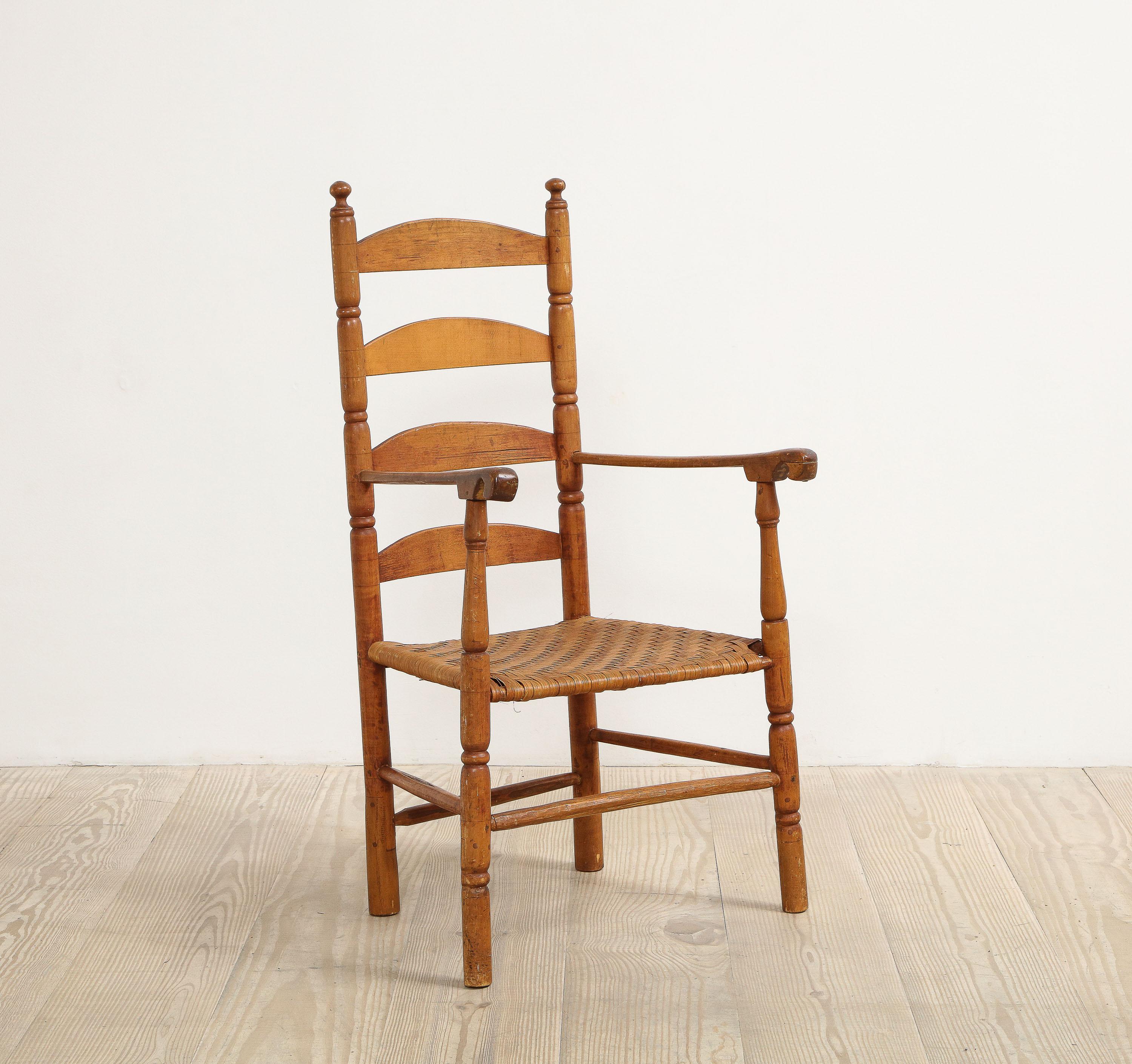 American shaker ladder back armchair, circa 1800, origin: New England, America, 

With distinctively carved arms, ring-turned details on front and back supports, bent slats, four stretchers and rush seat.