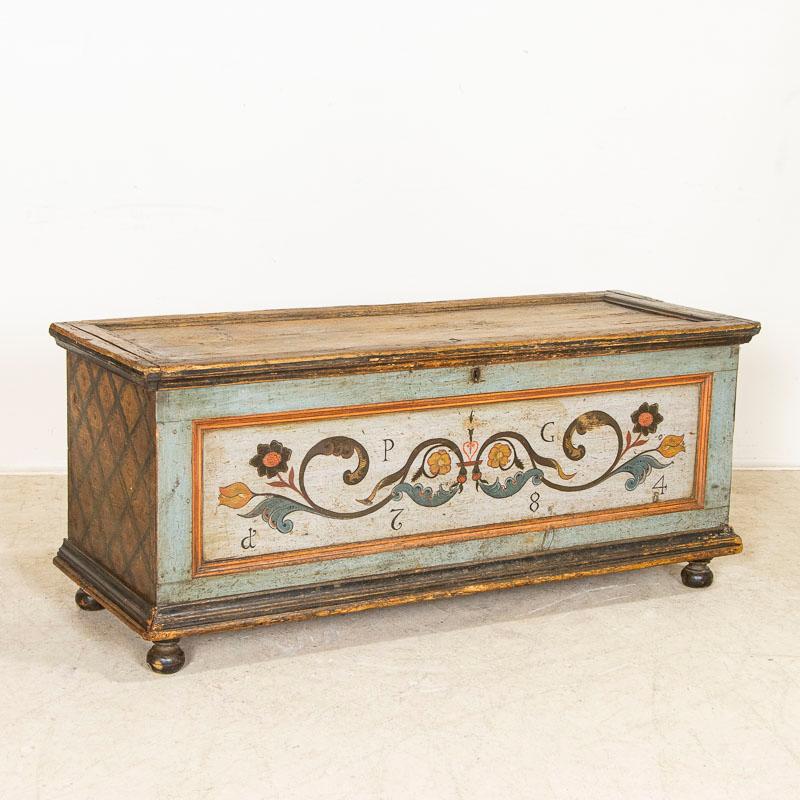 This lovely trunk is exquisitely painted in a soft blue with date of 1784 and monogram of PG clearly visible on the front. The delicate hand-painted scroll work and floral accents are perfectly executed while each side boasts painted lattice detail