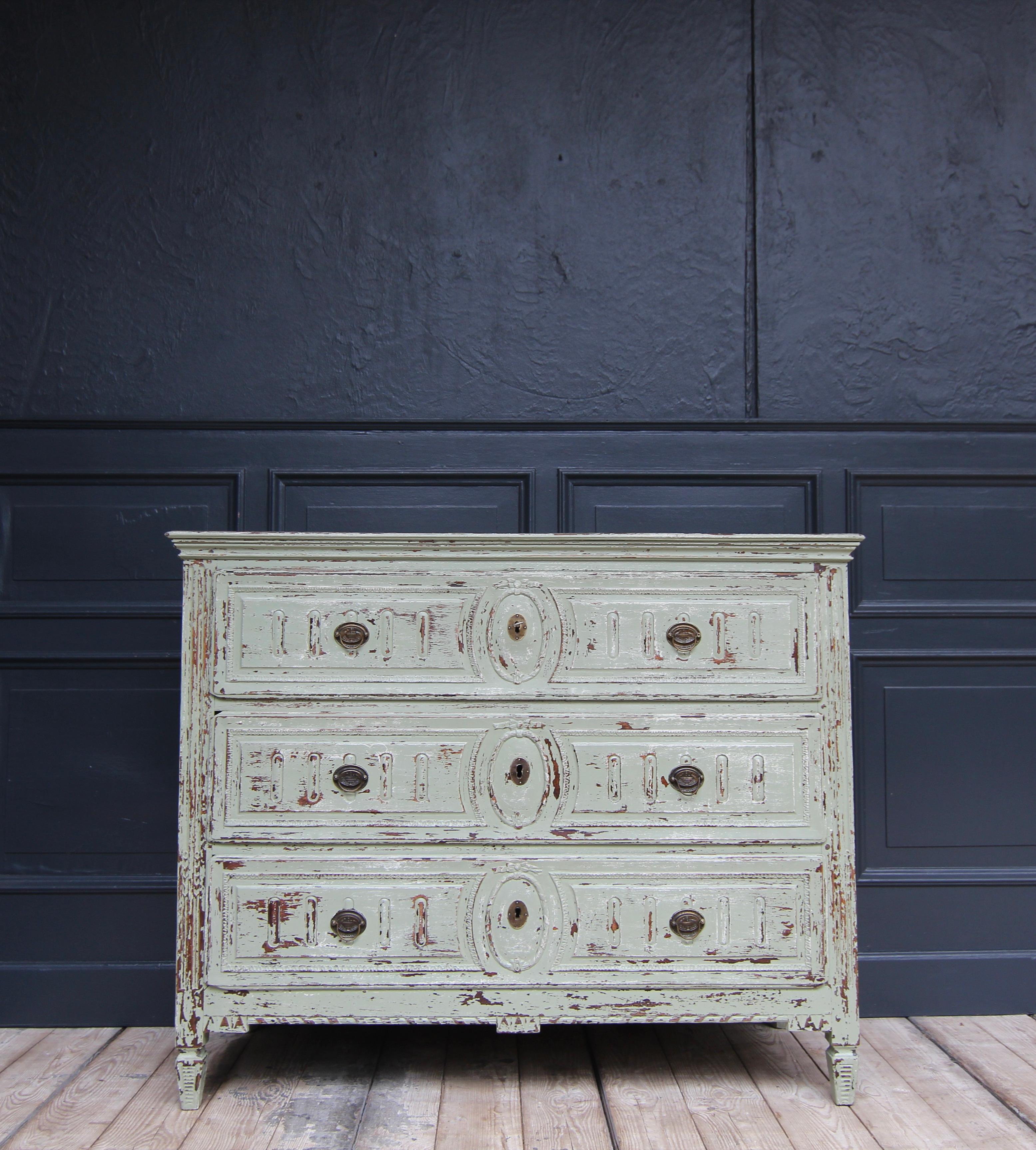 A classicistic Louis XVI chest of drawers from around 1800. Solid oak wood with later paint. 

Half-high side-cassetted corpus with slightly overhanging fluted profiled top and fluted pilaster strips ending in tapered square pointed feet. Three