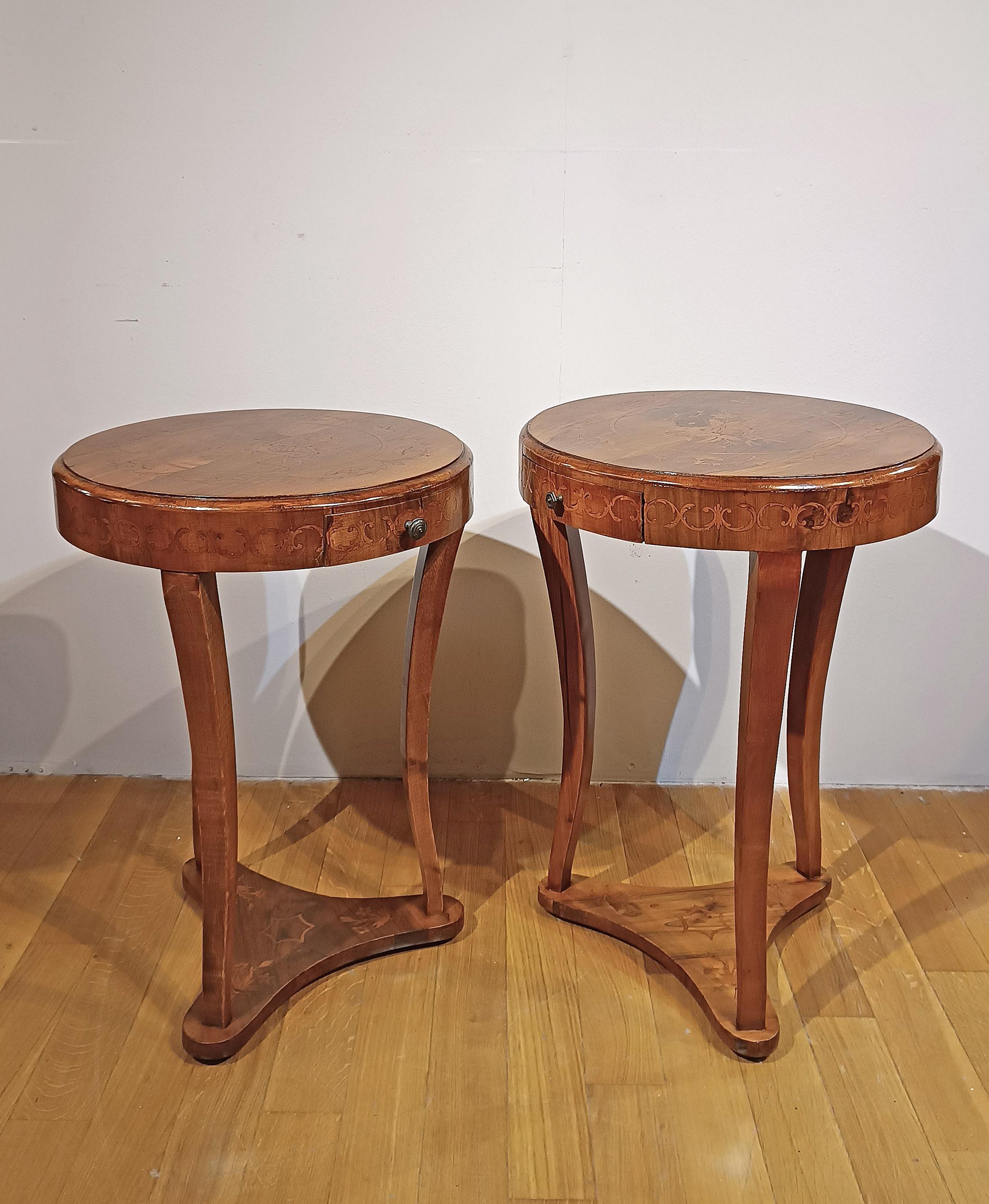 Elegantes Paar nussbaumfurnierter Couchtische mit raffinierten Intarsien aus Obstholz. Die Tische zeichnen sich durch ihre säbelförmigen Beine, die durch eine dreieckige Basis verbunden sind, und ihre flachen Platten mit elegantem Eulenschnabelrand