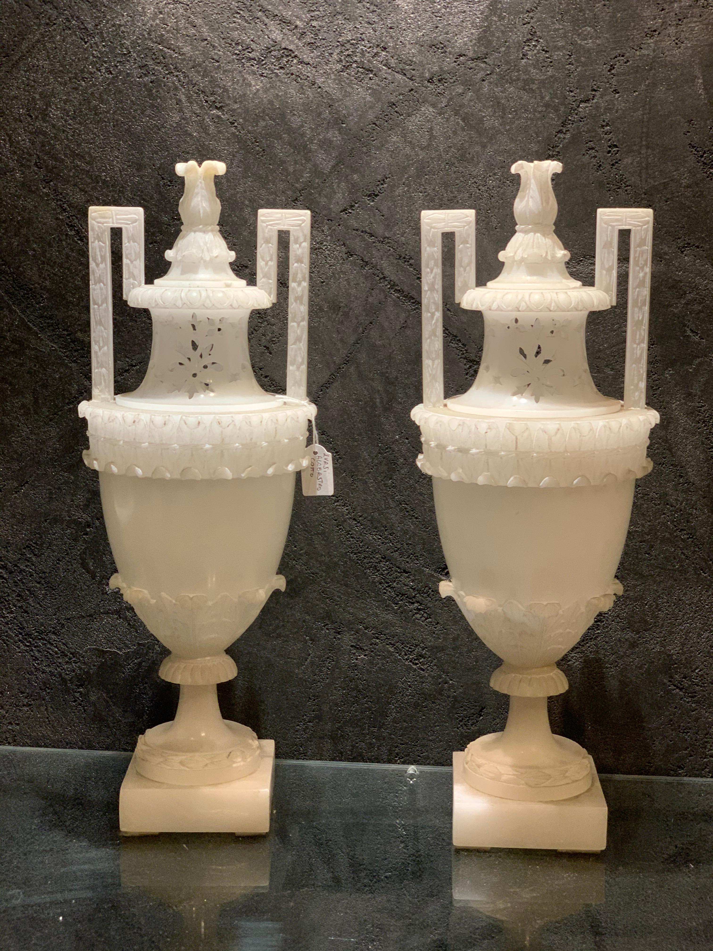 Elegantes Paar Amphora-Vasen mit Deckeln, die als Räuchergefäße dienen. Sie sind mit feinen Durchbrüchen versehen, um Düfte zu verströmen, und bestehen vollständig aus gekochtem Alabaster, der gekocht wurde, um sie weißer zu machen.
Dieses