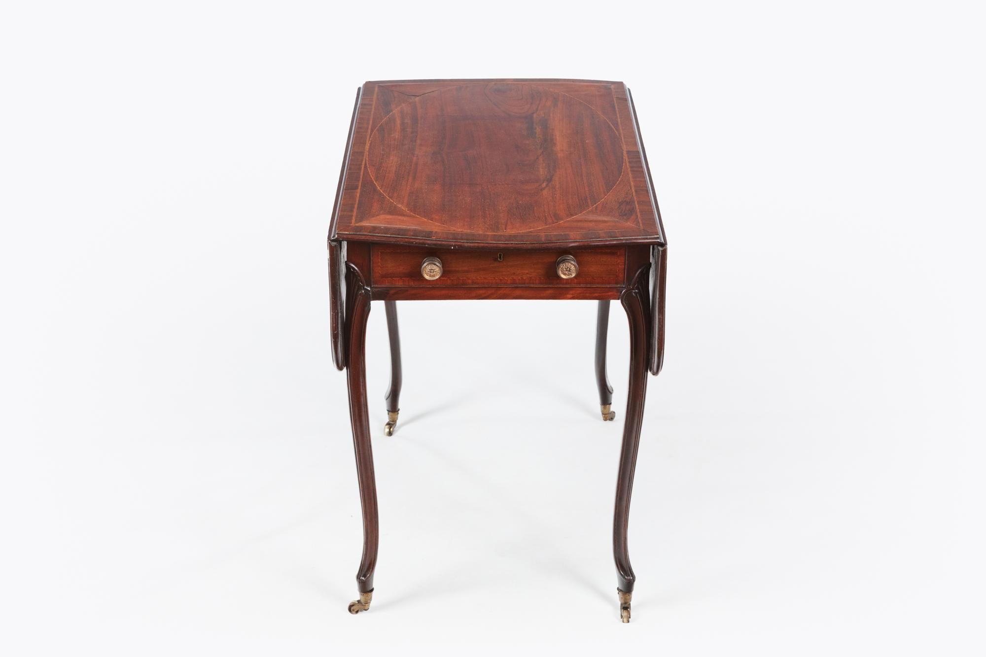 Late 18th century George III mahogany Pembroke table. The butterfly shaped top with satinwood crossbanding above a frieze drawer and opposing sham drawer, on fan-carved cabriole legs ending in molded feet raised on caps and leather casters. After