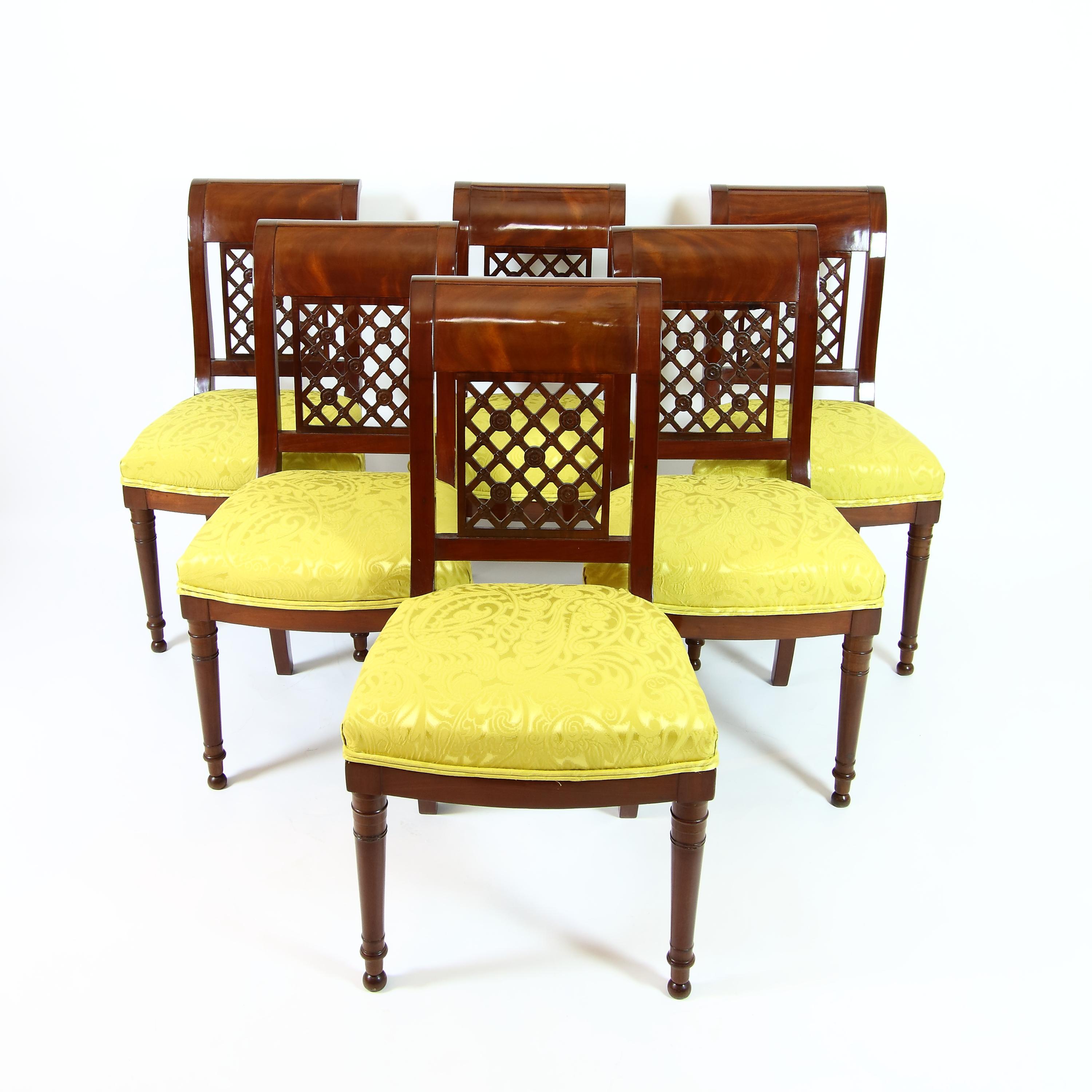 Set of six sidechairs raised on circular front legs and square curved back legs, backrest with carved pierced latticework, the intersections of which are decorated with stylised rosettes, the top rail curved backwards. All side chairs are