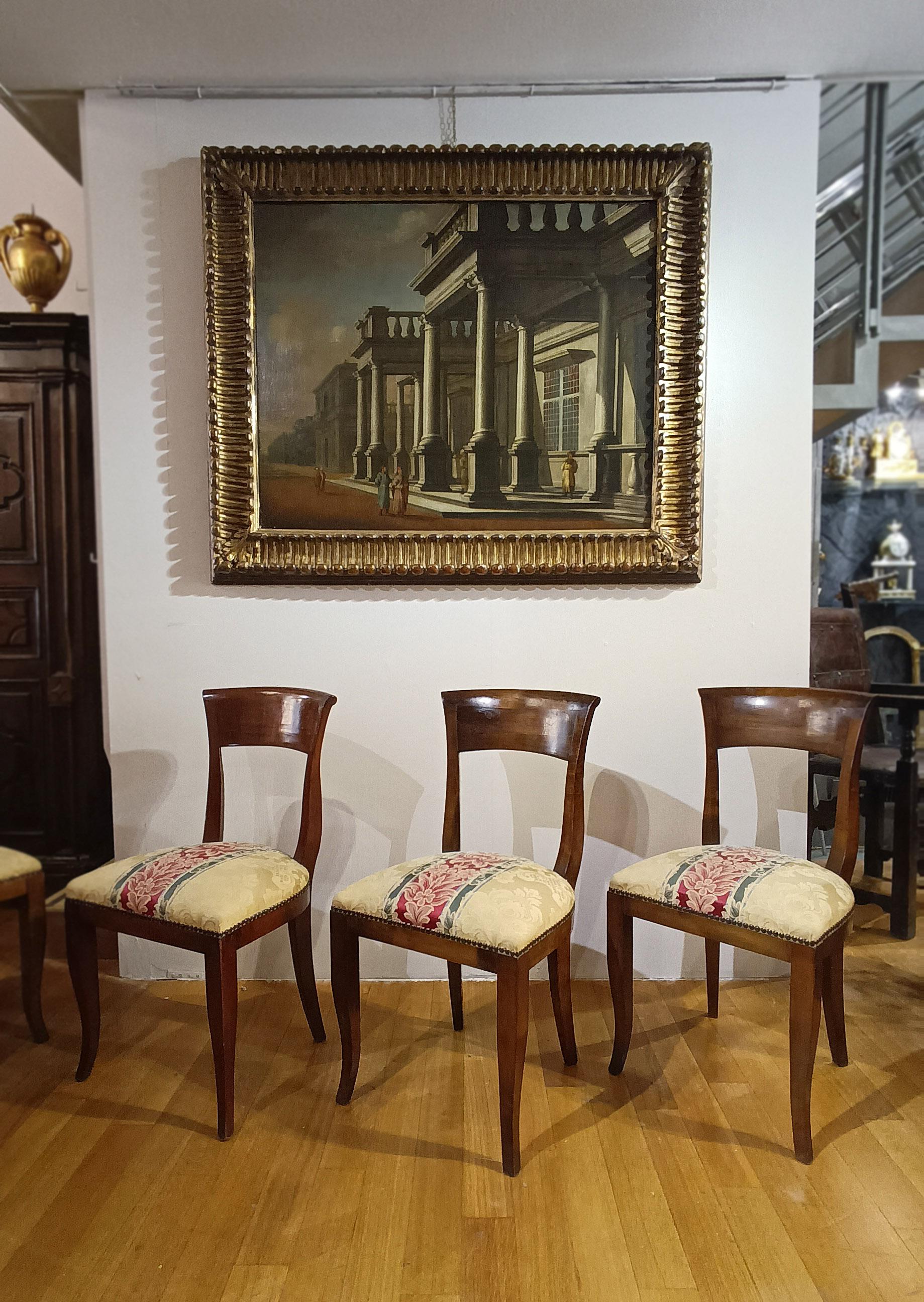 Elegant set of six chairs in solid carved walnut, embellished with original fabric with plant embroidery in shades of gold, green, and pink. The chairs are distinguished by their curved, saber-shaped legs, typical of the period, offering comfort and