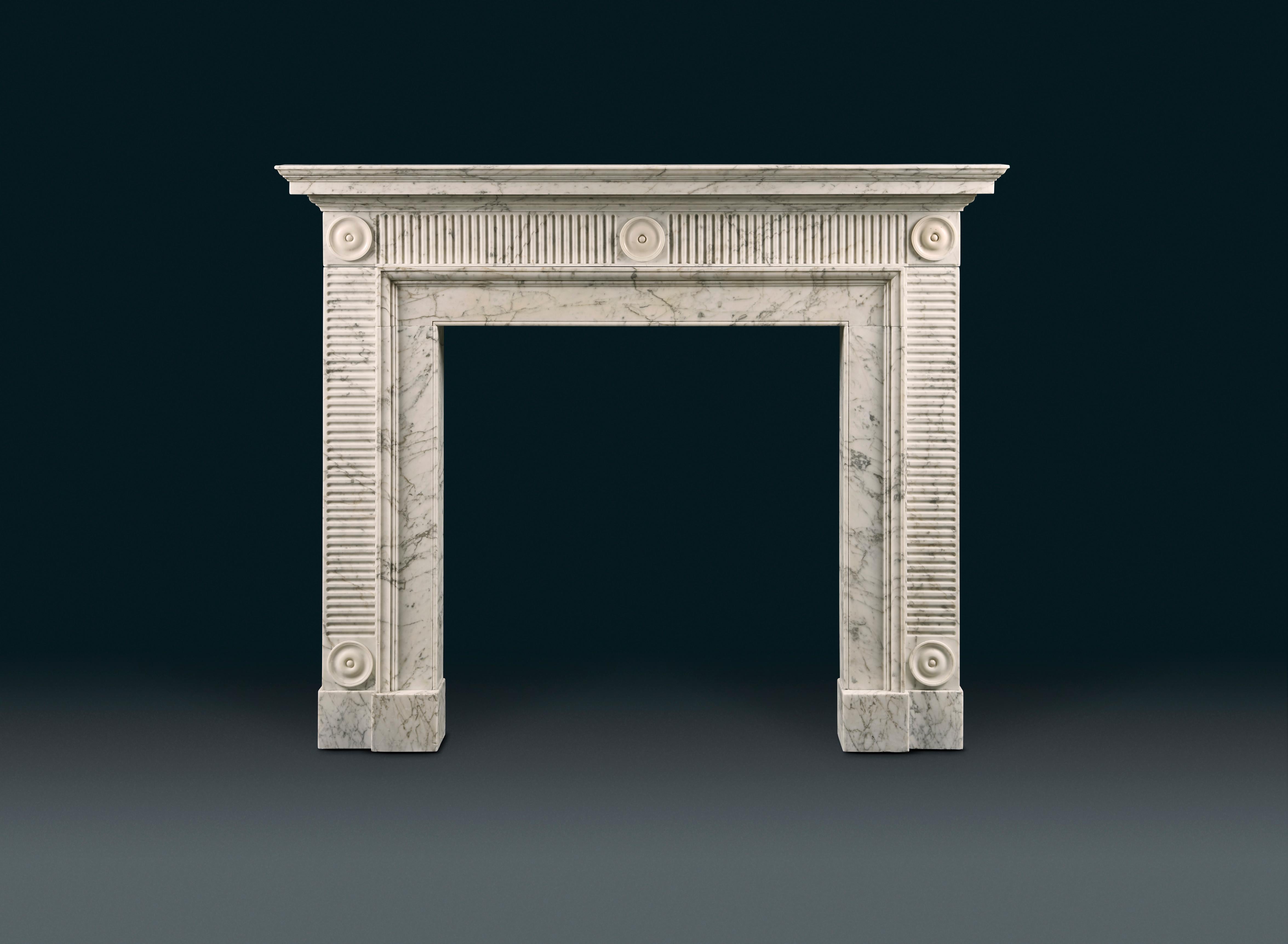An elegant late 18th century Carrara and white statuary marble chimneypiece in the manner of Sir John Soane. Once installed in the famous Waldorf Astoria Hotel in Manhattan. With a tiered and moulded shelf, the frieze and jambs with horizontal and