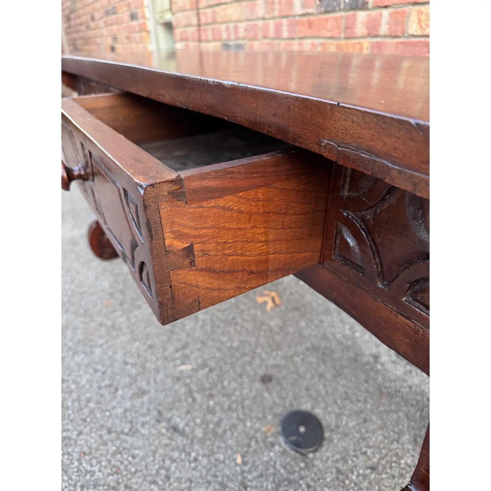 Add an elegant focal point to your study or library with this antique Baroque carved console. Carved in Spain c. 1750 and built of solid walnut wood, the trestle table stands on two carved legs with scroll motifs. The long table features two drawers