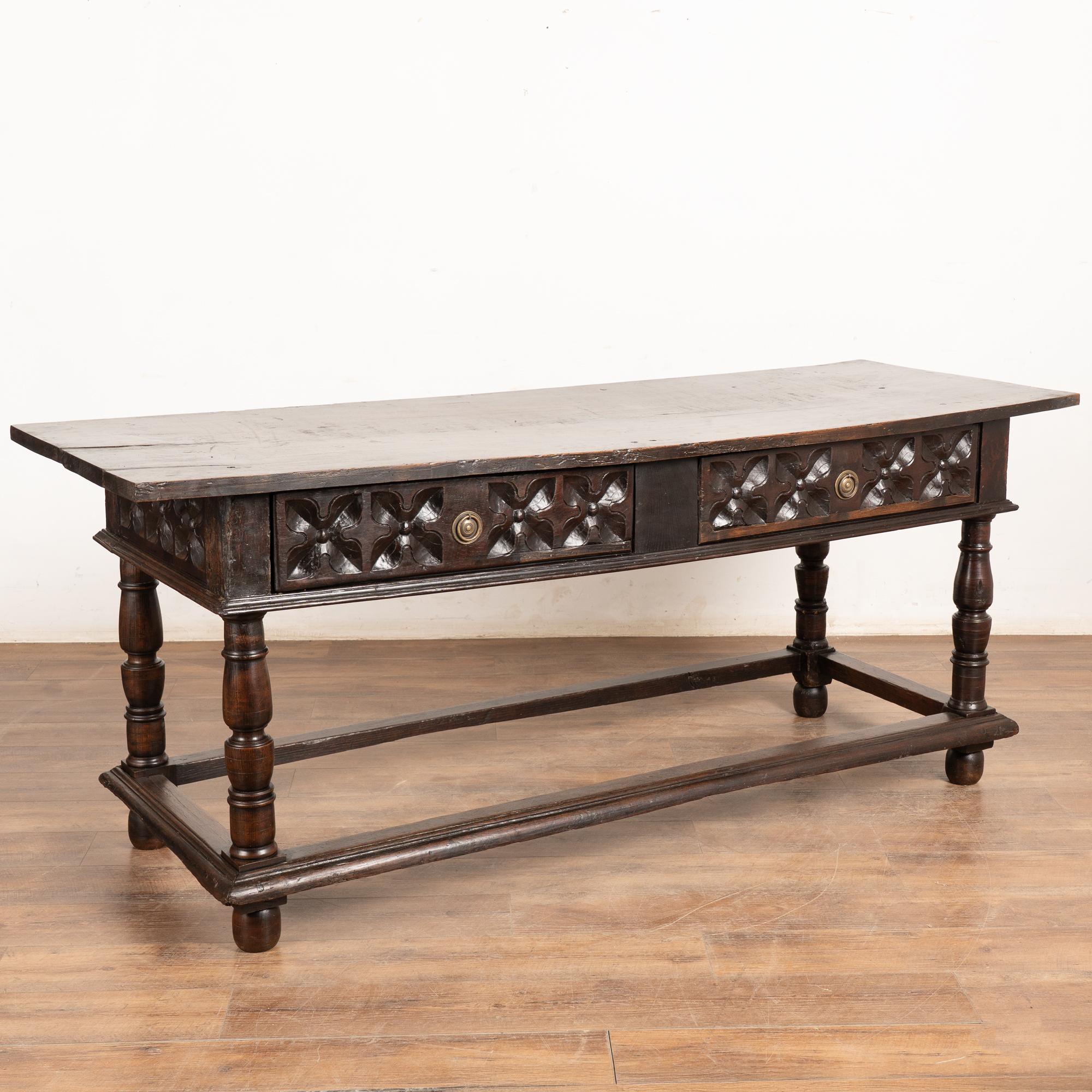 Dark oak console table with two drawers resting on trestle base from Spain. Note the deep carving along each drawer front.
Please enlarge photos (especially of top) to appreciate the dark patina of the wood, including old cracks, gouges, stains,