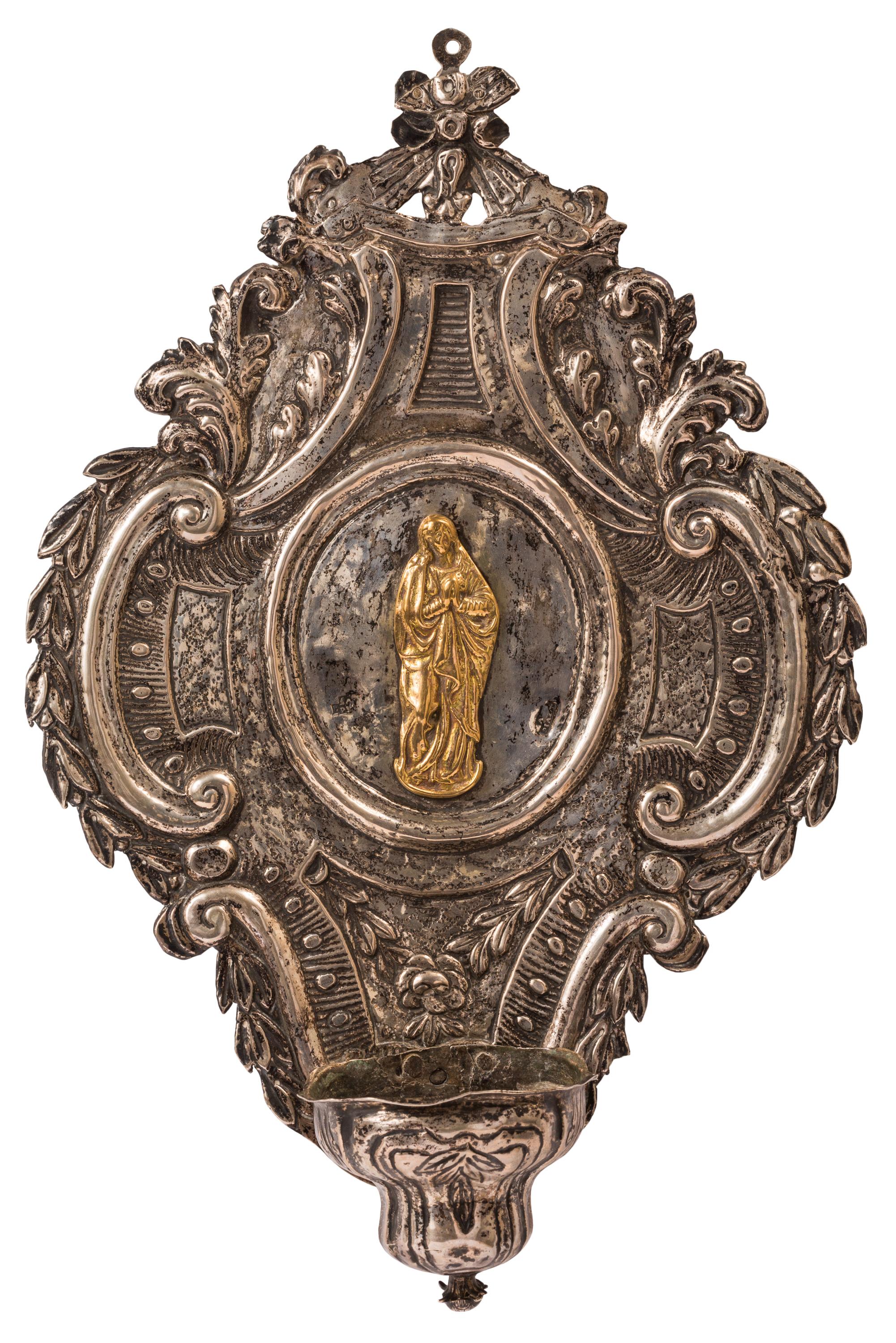 This highly decorative silver holy water font or stoup, is stamped with hallmarks placing its manufacture in Aspiazu, Bilbao, Spain during the late 18th century. The raised figure of the Virgin Mary at the center is silver gilt (or vermeil), in