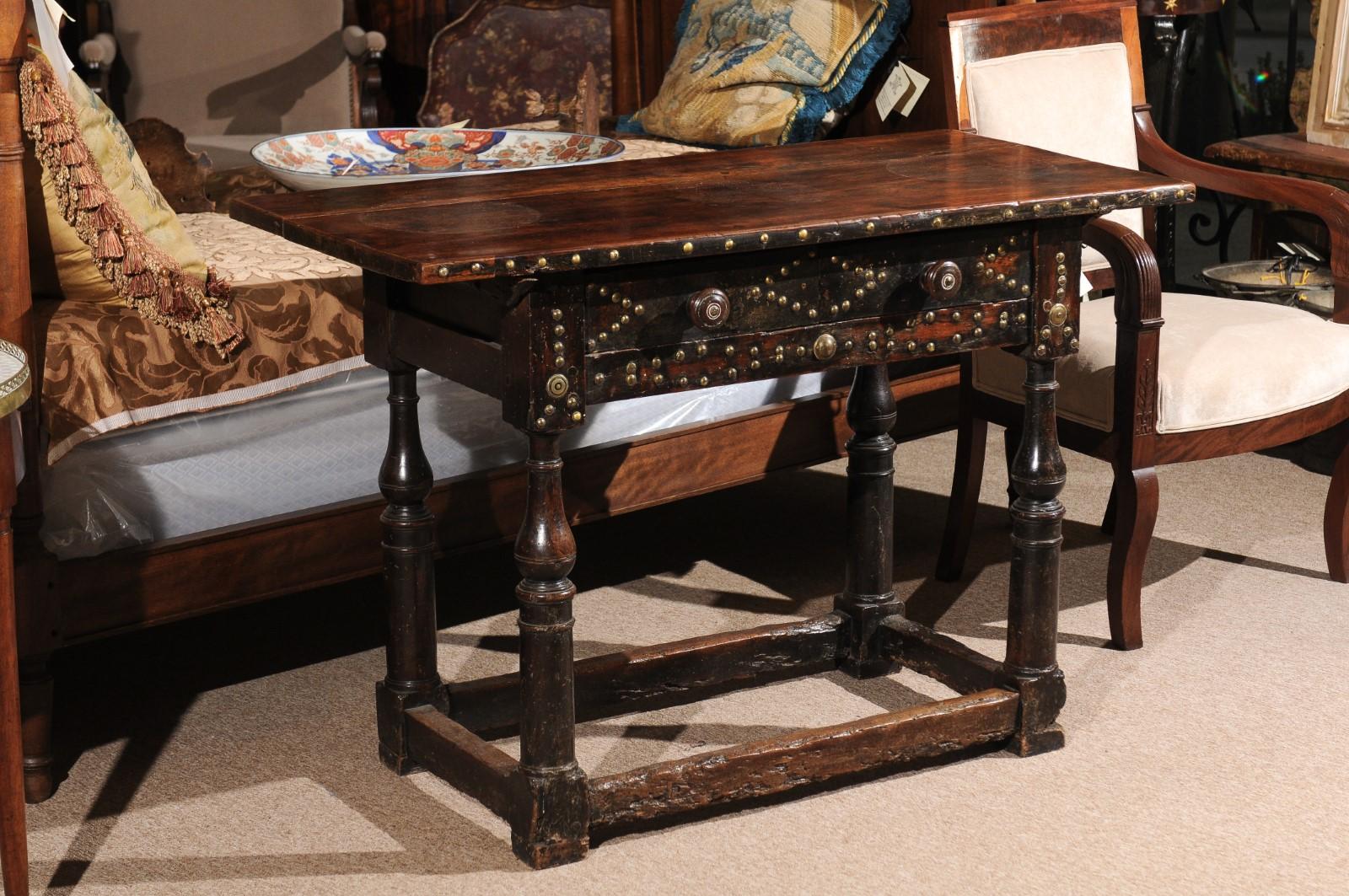The late 18th century Spanish walnut console table in the Baroque style with rectangle top, brass studs on front part of table including drawer front with geometric design. All resting on turned legs and stretcher.

 