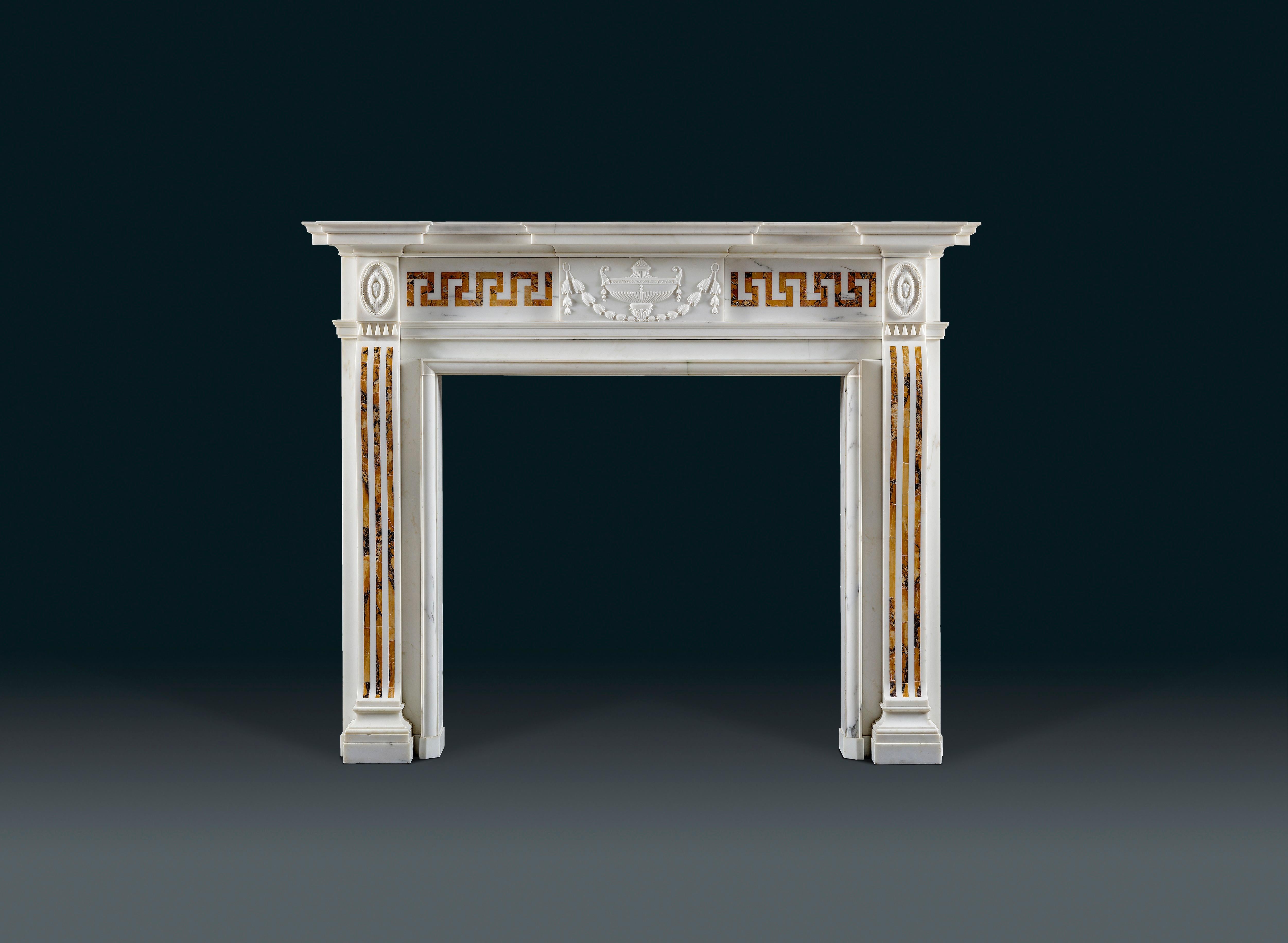 A late 18th century statuary and Siena fireplace of late 18th century neoclassical design, the frieze with a statuary marble tablet decorated a classical urn and swag flanked by Siena inlaid frets, and the console shaped jambs inlaid with Sienna