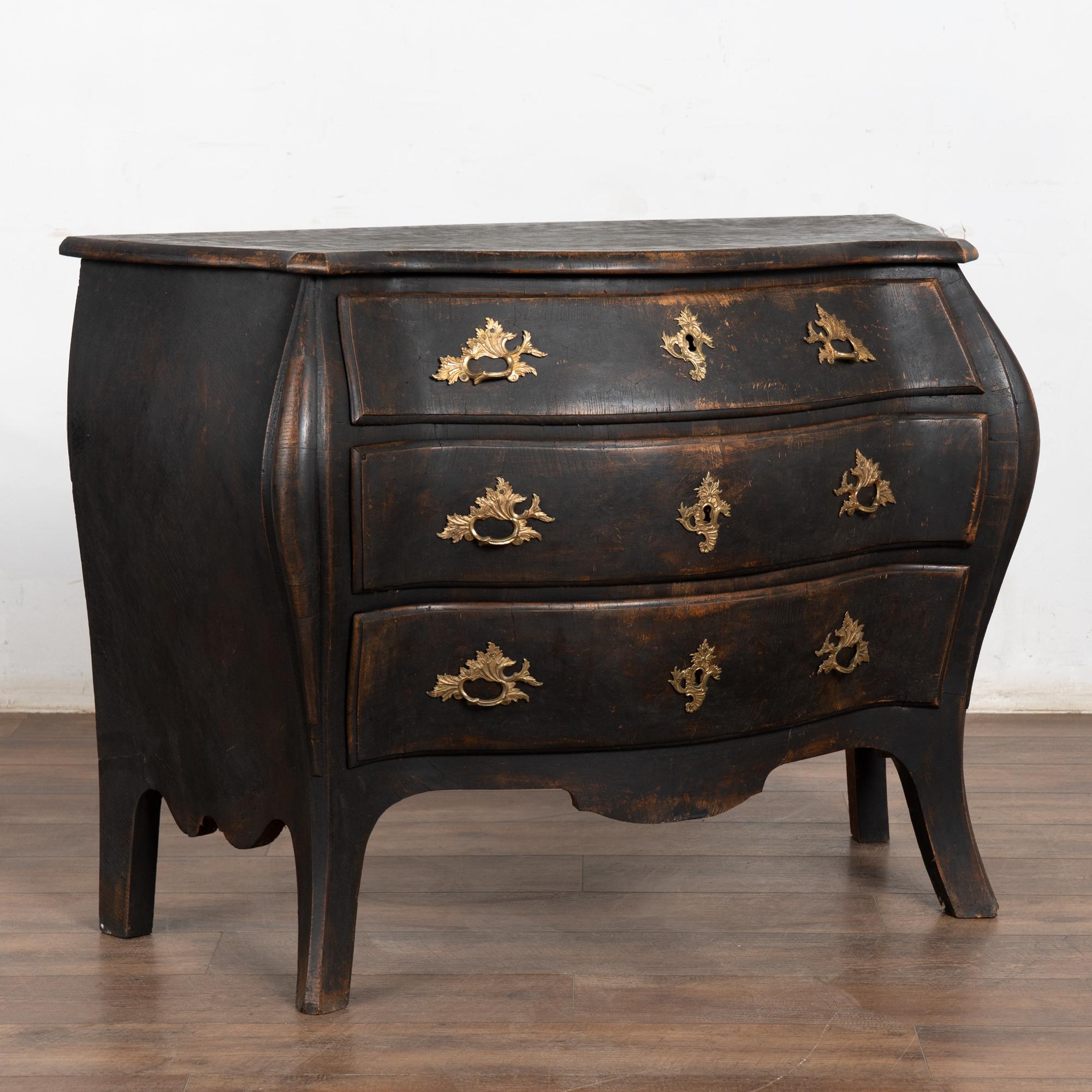It is the Bombay curves and saber feet turning gently outwards that draws one to this dramatic pine chest of drawers.
Restored, strong stable and ready for use. The old but later applied black paint has been distressed and reveals the age and