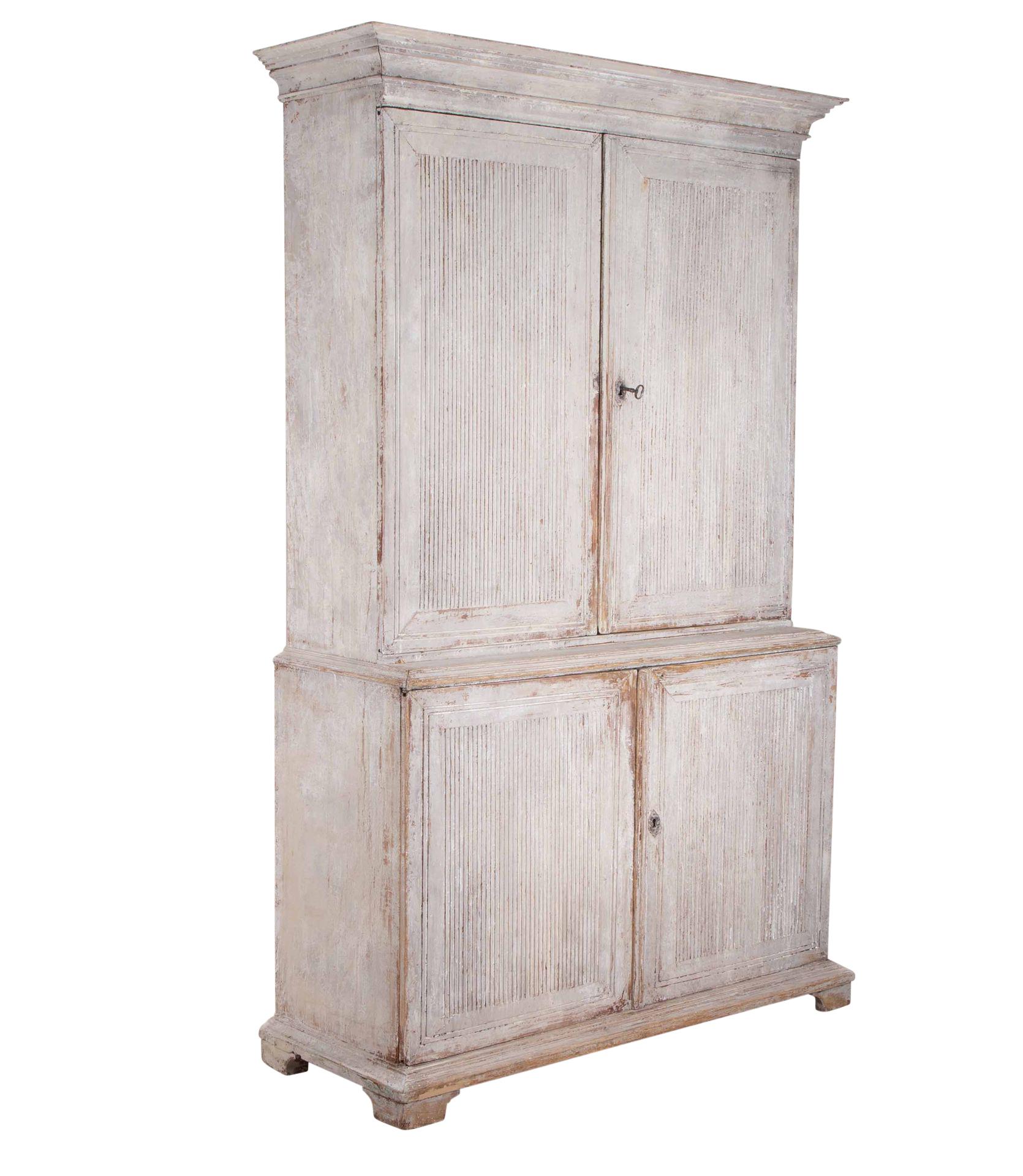 Cabinet suédois de style gustavien de la fin du XVIIIe siècle.
Avec fronton décoratif sculpté, deux grandes portes et une façade cannelée. S'ouvrant sur des étagères de rangement, sous deux autres portes aux façades cannelées, s'ouvrant sur d'autres