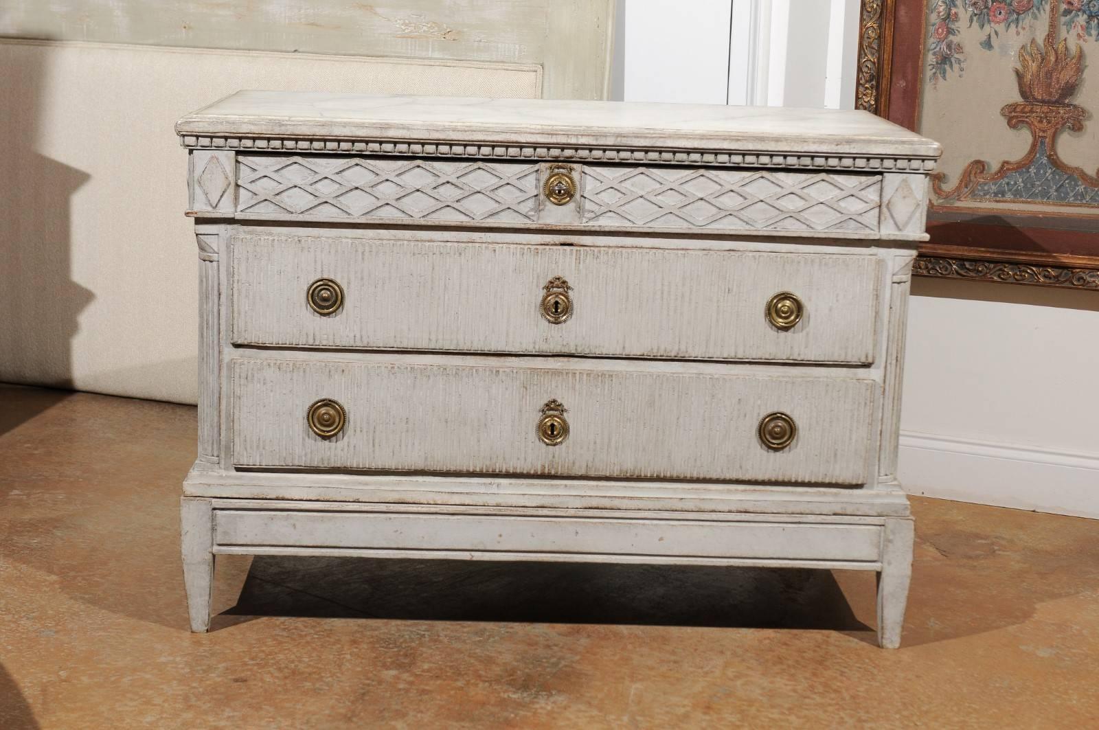 A Swedish period Gustavian three-drawer commode from the late 18th century, with original hardware, marbleized top, trellis motifs and reeded drawers. This exquisite Swedish chest features a slightly raised rectangular faux-marble top, sitting above
