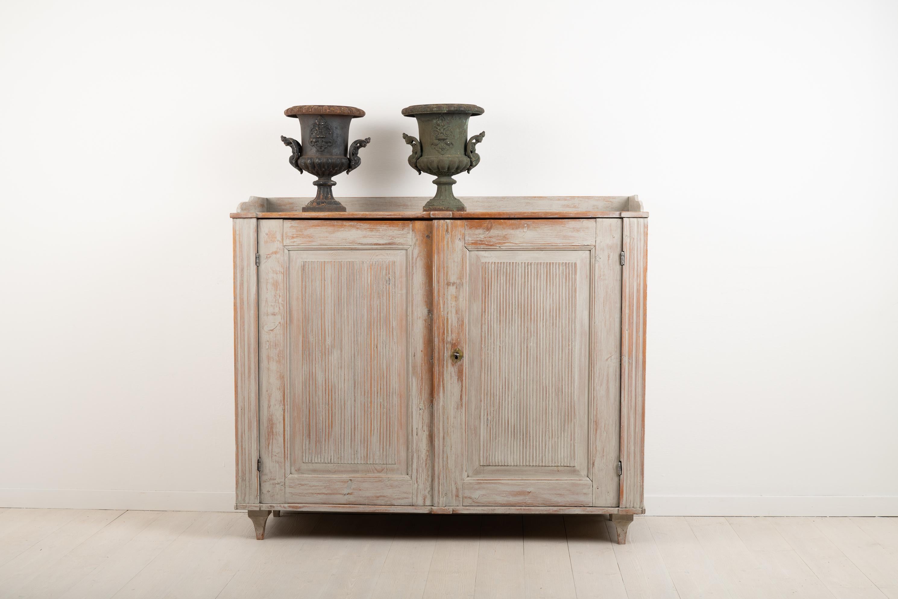 Swedish neoclassic sideboard from the late 18th century. The sideboard is from northern Sweden and is made from Swedish pine. It has hand carved wooden decorations such as the ribbed panels on both doors. The lock and key are in fully functional