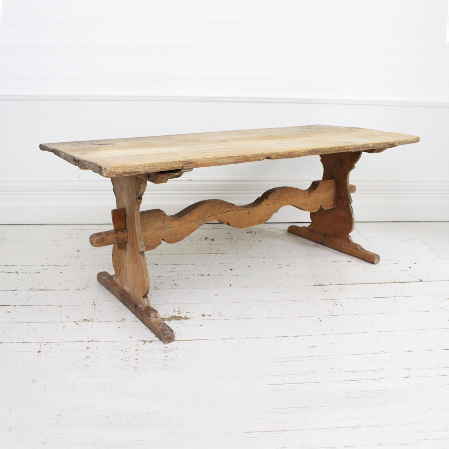 This is a very rare Swedish trestle table - mainly because of it's unique and distinctive shaped rail. It dates from circa 1790-1800. Typical early features include the top with it's axed boards underneath and the shaped end supports. In practical