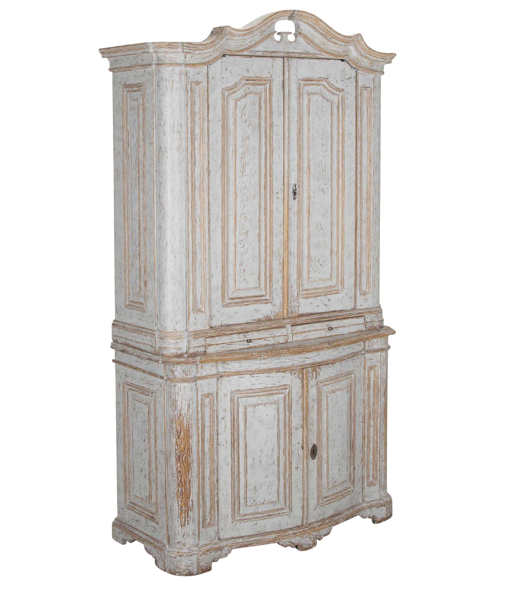 Cabinet rococo suédois de la fin du XVIIIe siècle.
Avec un fronton décoratif profondément sculpté. Avec des détails sculptés sur les portes ouvrant sur un espace de rangement, sous une base en arc de cercle, avec deux autres portes ouvrant sur un