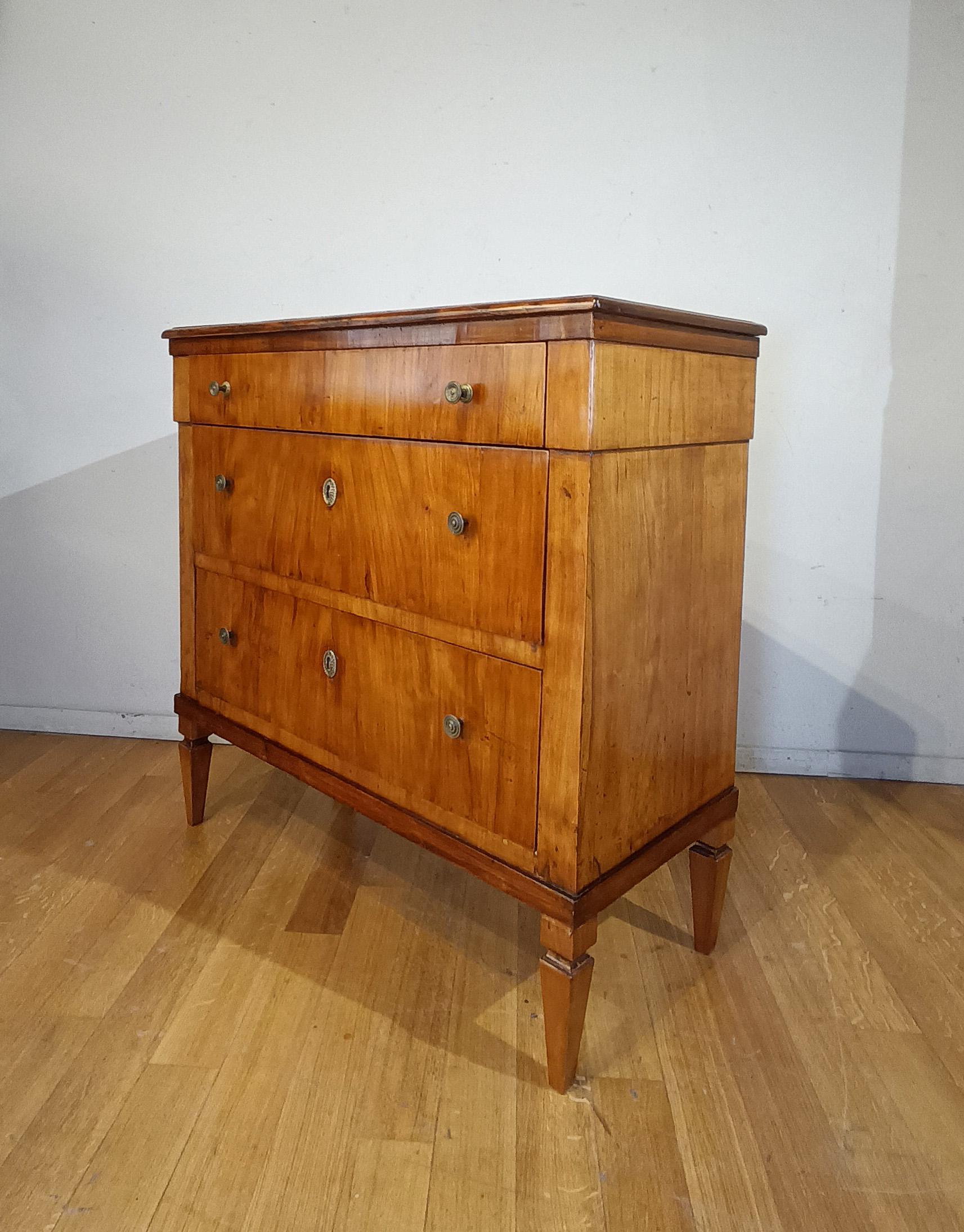 Schöne Kommode mit kleinen Abmessungen, aus massivem Kirschbaumholz, handgeschnitzt und in Kirsche furniert. Die Kommode hat pyramidenstumpfe Beine und drei ergonomische Schubladen, die sich ideal zum Aufbewahren von Gegenständen eignen. Die
