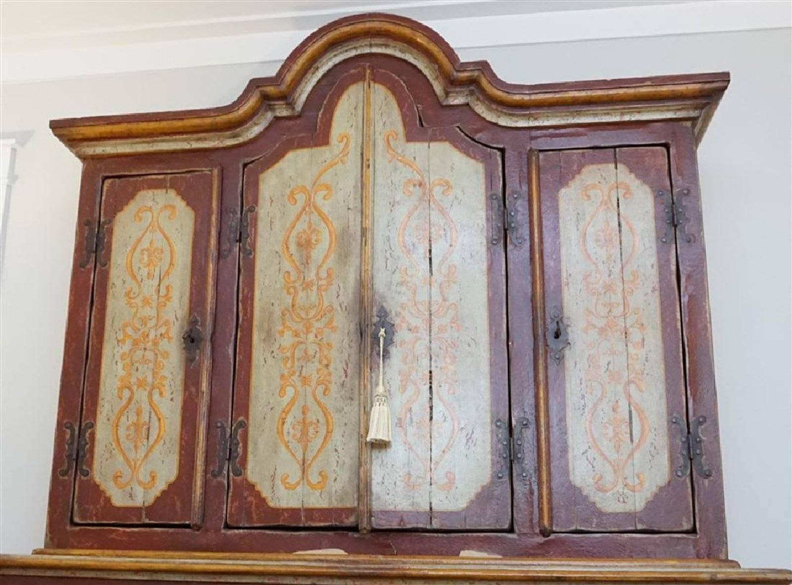 Late 18th century Tyrolean tall cabinet. Made in two parts with arched cornice above four paneled and decorated doors concealing shaped shelves. The lower section with four further paneled doors all retaining the original painted decoration. Tyrol