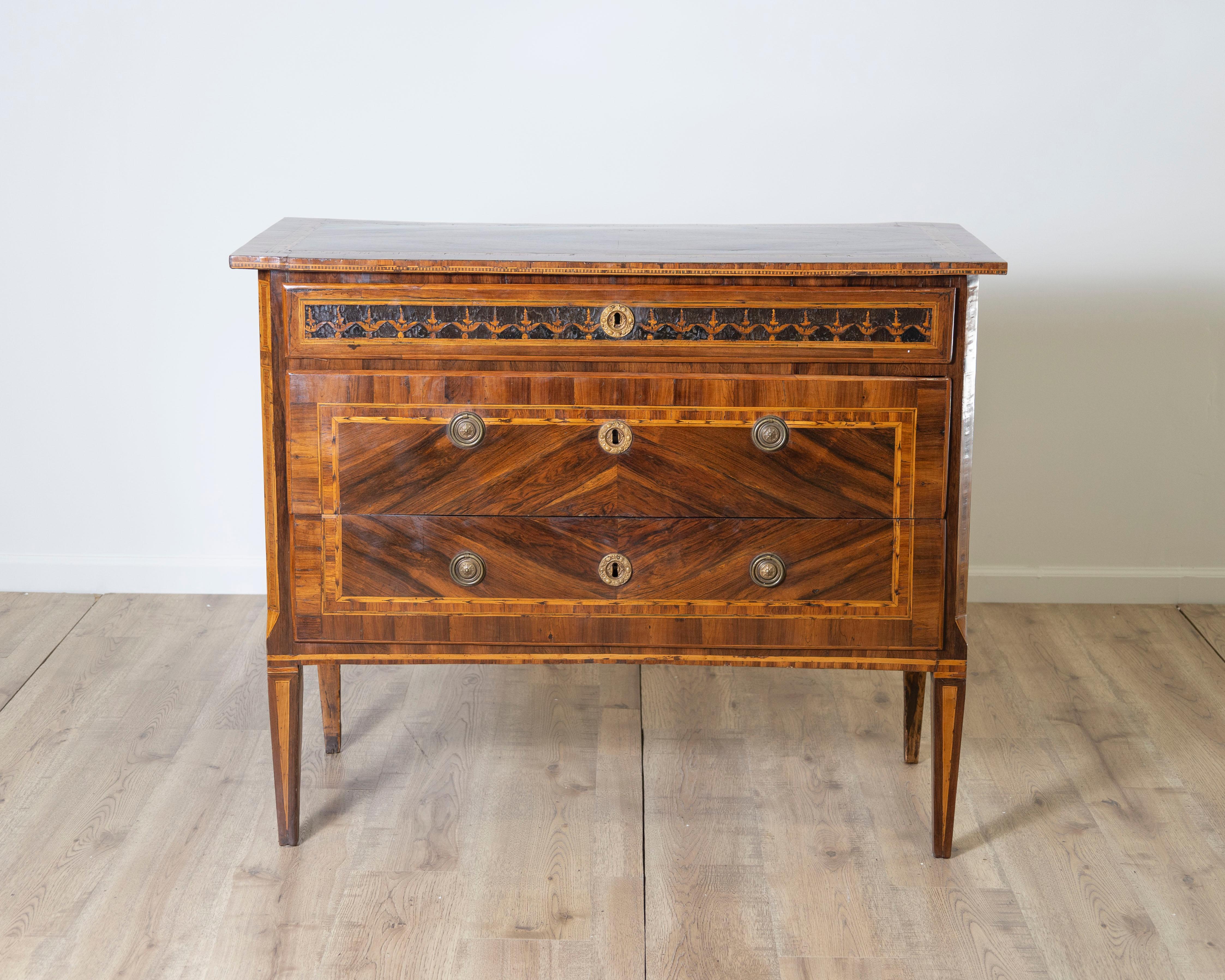 A beautiful and refined Louis XVI period chest of drawers, crafted in Italy in the late 18th century and veneered in rich walnut with exquisite inlay work. This elegant piece features three drawers—two deep and one narrow—expertly rebated into the