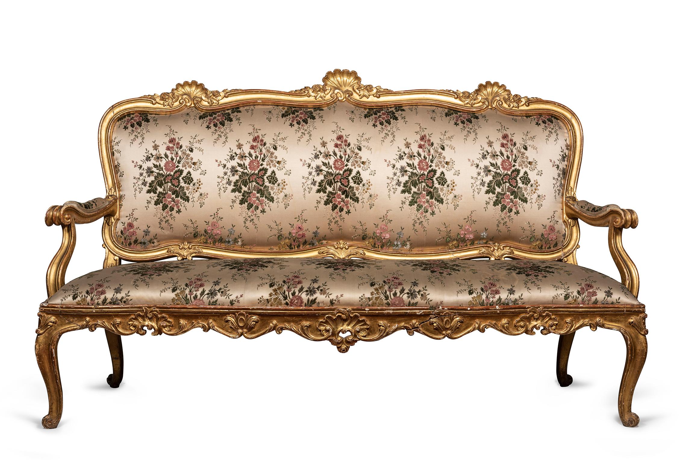 Comprised of a three-seat canapé and pair of fauteuils, the exposed giltwood frames decorated with rocailles, rosettes, acanthus and C-scrolls, the cartouche back, seats and padded arms upholstered in pale pink silk, embroidered with repeating