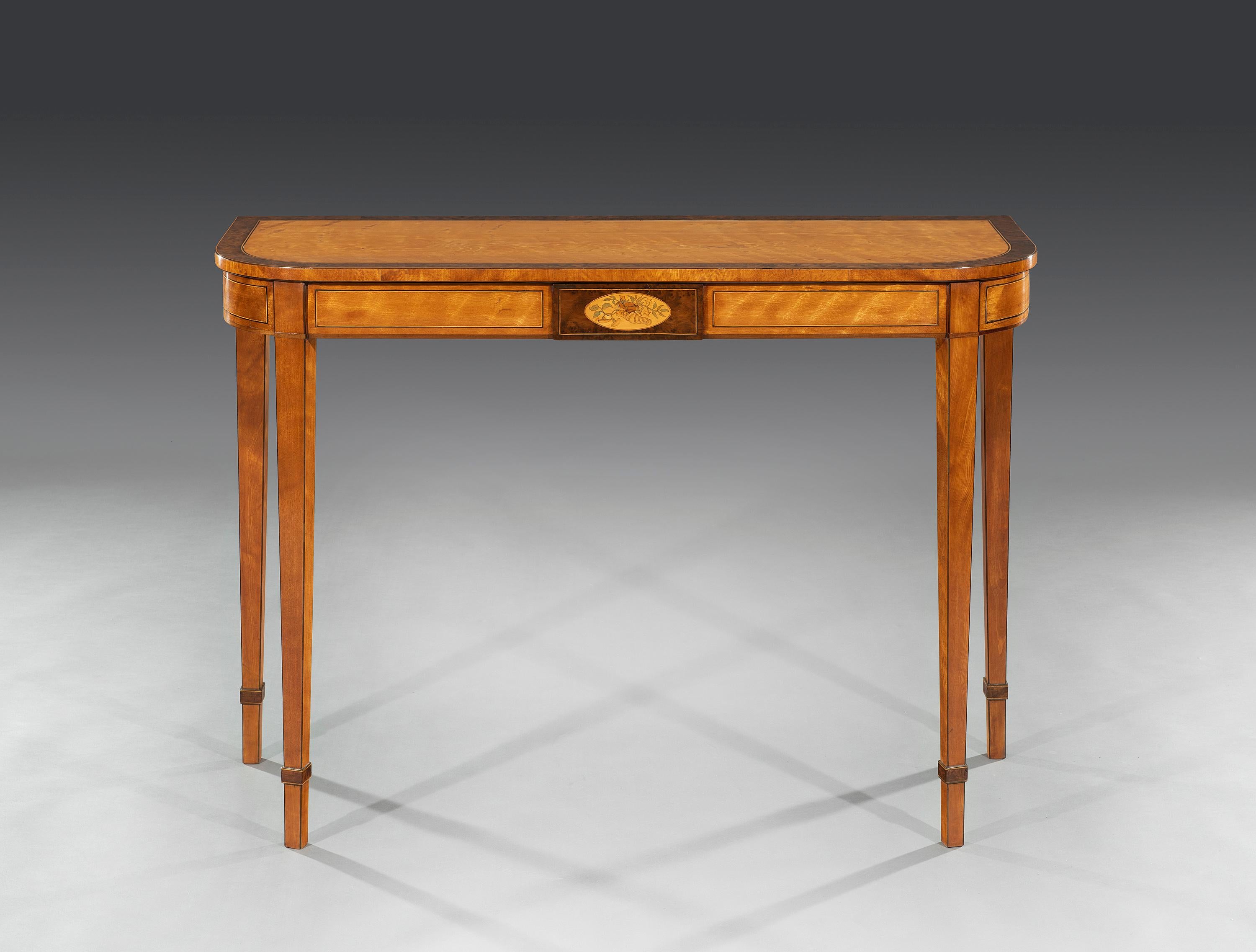 The top is crossbanded with burr yew and boxwood stringing above a banded frieze and floral marquetry inlaid centre panel. The table stands on finely tapered legs.