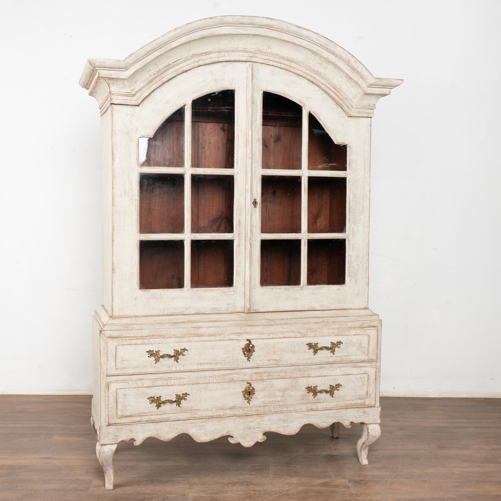 Un grazioso cofano ricurvo incorona questa straordinaria vetrina o espositore, che poggia su due ampi cassetti e su piedi curvi cabriolet.
Le ante superiori in vetro mettono in bella mostra qualsiasi collezione contenuta al loro interno, dalle