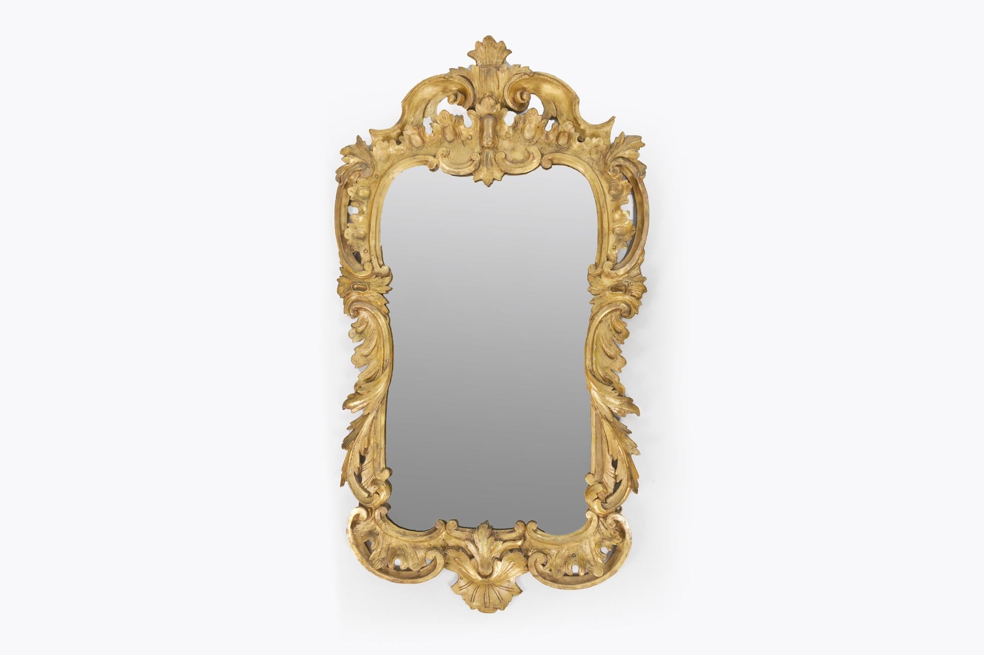 Miroir en bois sculpté et doré de la fin du XVIIIe siècle ou du début du XIXe siècle. Cadre à décor sculpté d'acanthes, de C.I.C. et de rinceaux. Dans le style rococo. Avec verre d'origine.