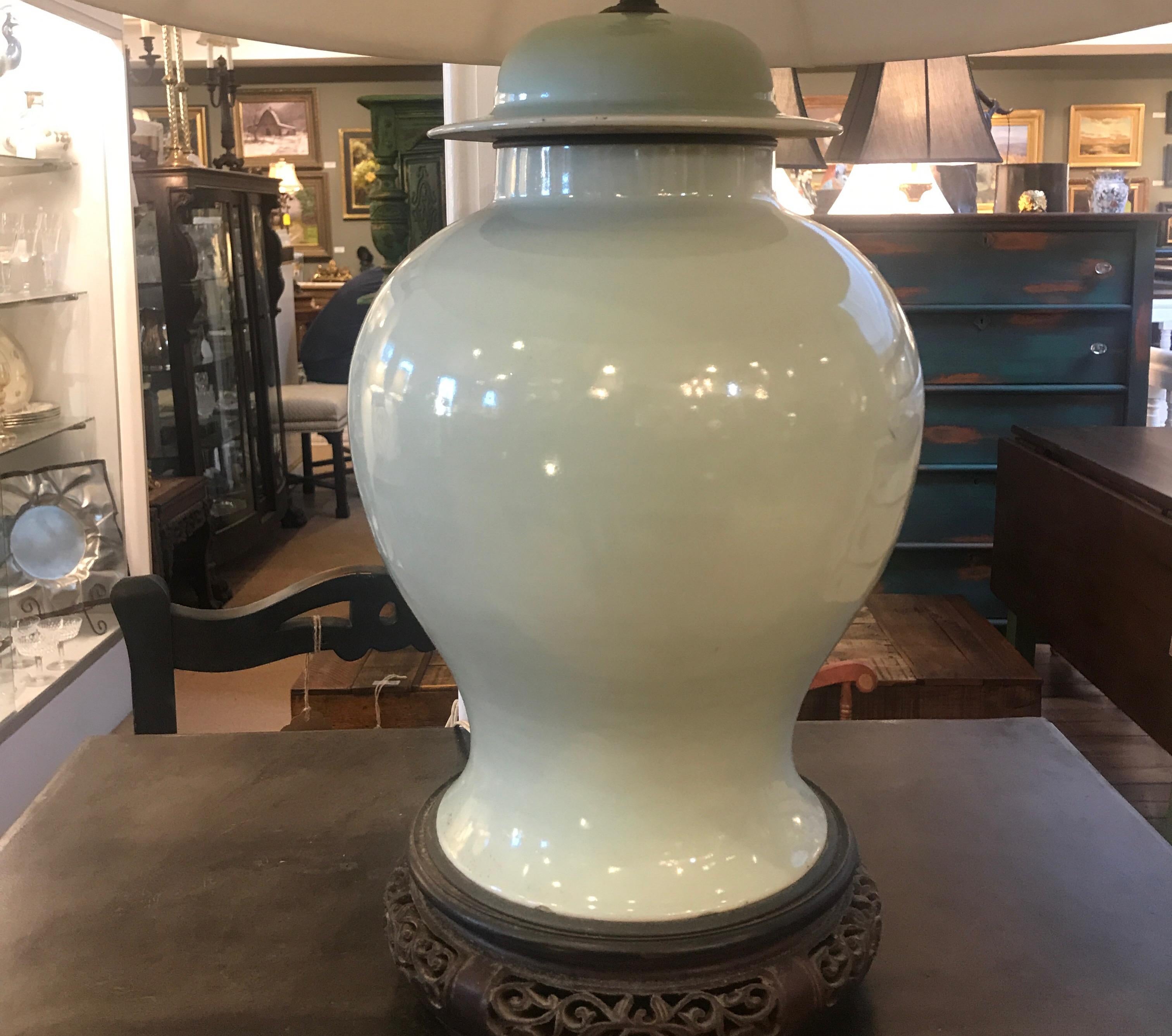An very early Chinese celadon porcelain jar with hand carved hardwood base, now as a lamp,. The pale celadon from the early part of the 19th century or earlier with a fine carved hardwood base. Lamped in the early part of the 20th century. The shade