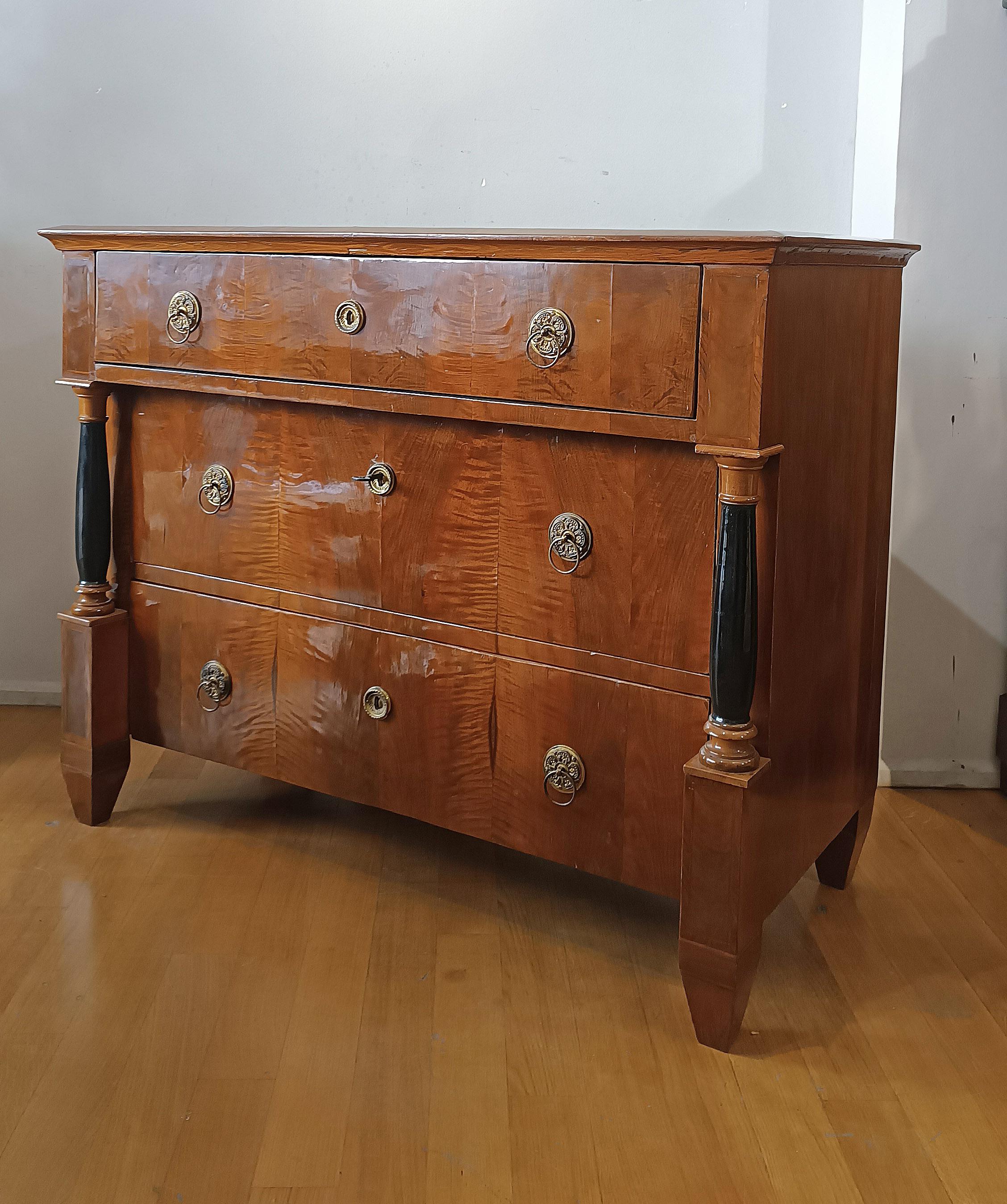 Elegante cómoda con escritorio deslizante, chapada en nogal fino. La cómoda tiene patas troncopiramidales, típicas de finales del siglo XVIII, mientras que el exterior y las columnas reflejan el estilo y la época del Imperio de principios del siglo